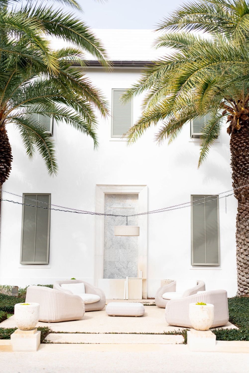Minimalist outdoor terrace with palm trees and white modern furniture.