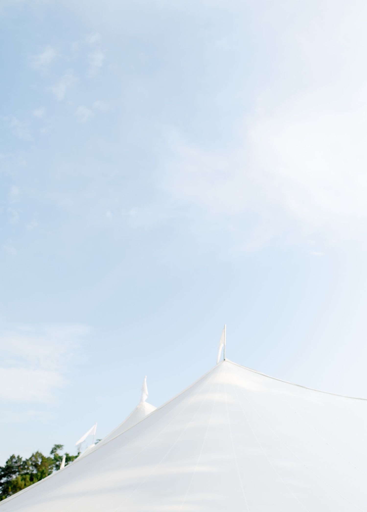 Minimalist view of white tent peaks against light blue sky.
