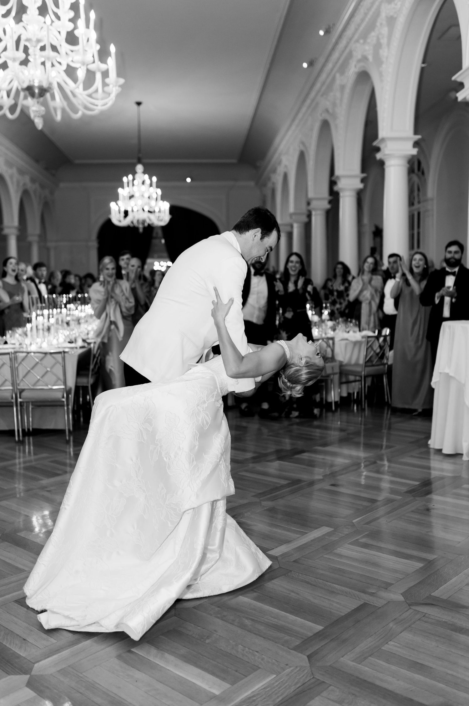 A romantic first dance sequence at an elegant wedding reception with crystal chandeliers and hardwood floors.