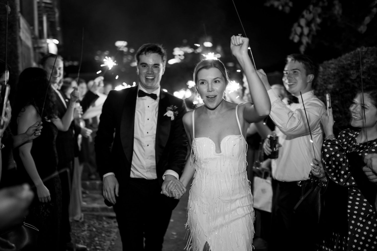 Wedding reception guests dancing and celebrating on a dark dance floor.