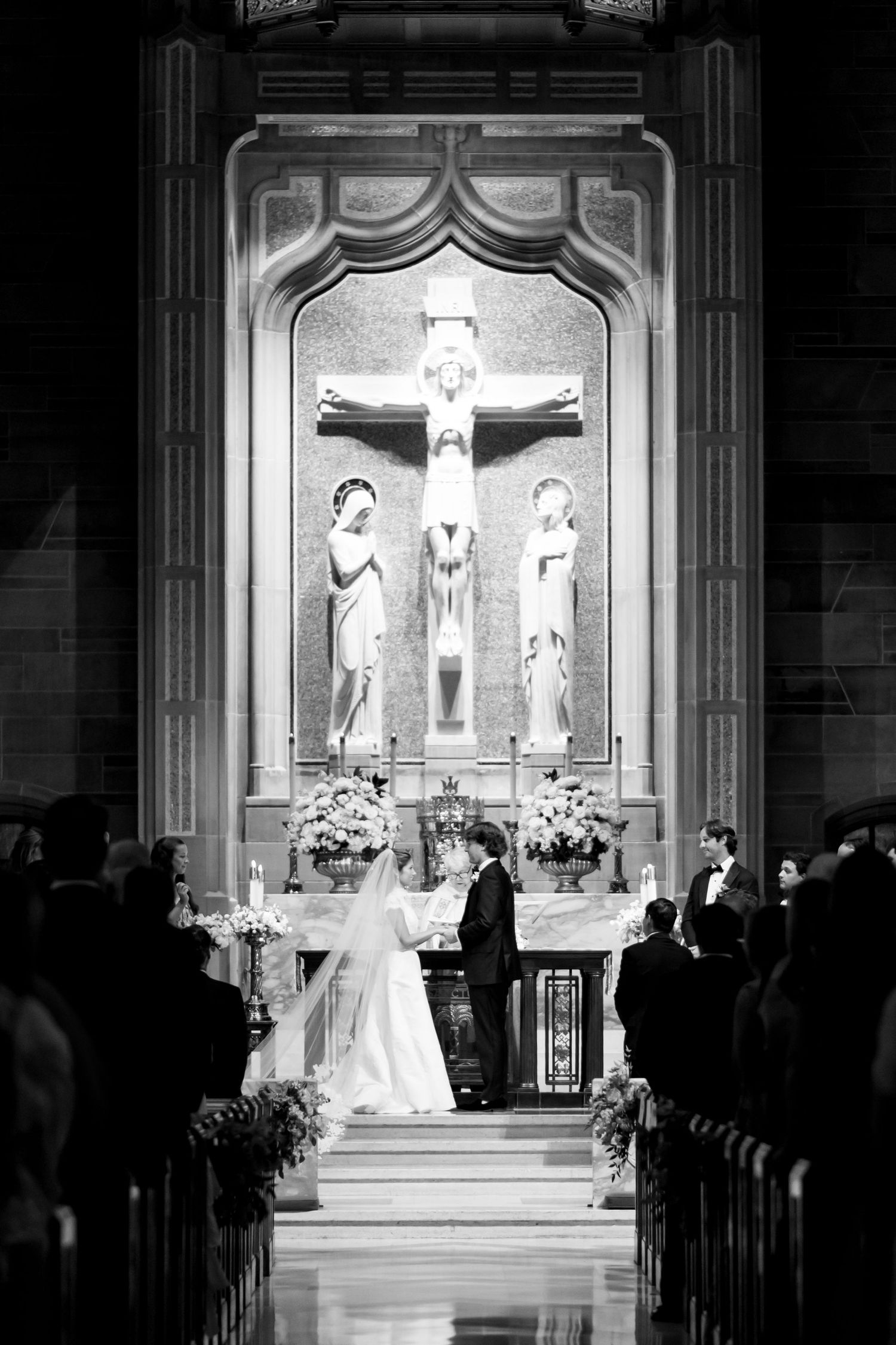 Church altar during wedding ceremony with dramatic lighting and crucifix centerpiece.