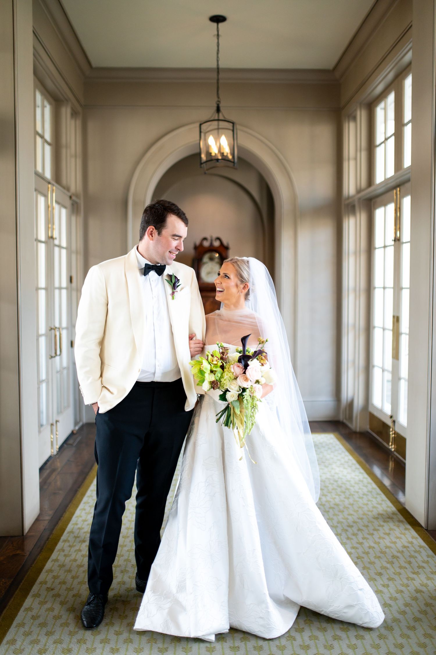 Indoor wedding portraits in an elegant hallway with natural light streaming through windows.