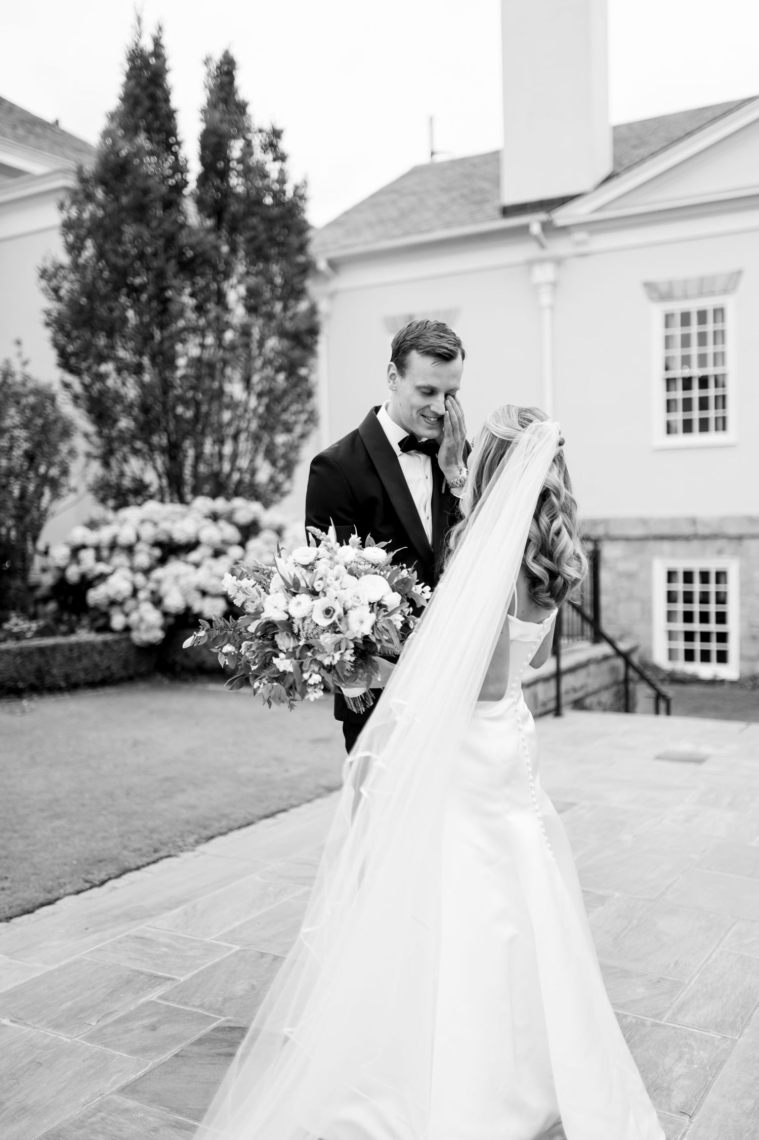 Black and white wedding portrait with couple sharing intimate moment outdoors.