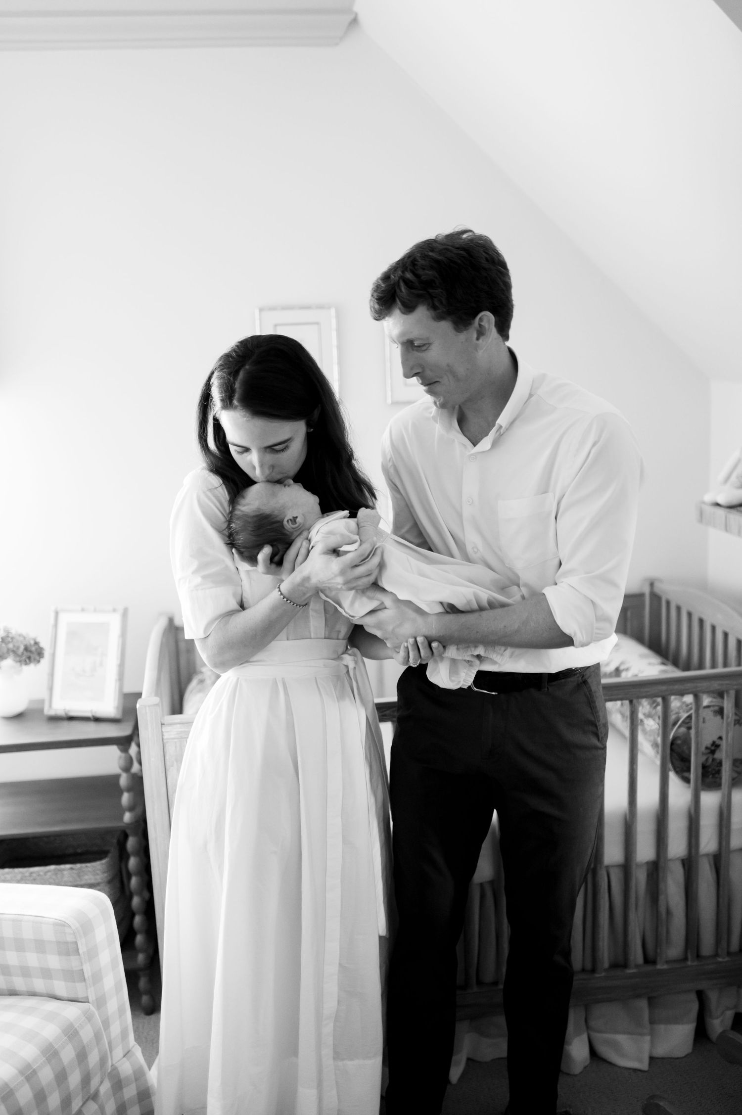 A black and white nursery photograph capturing a tender family moment.