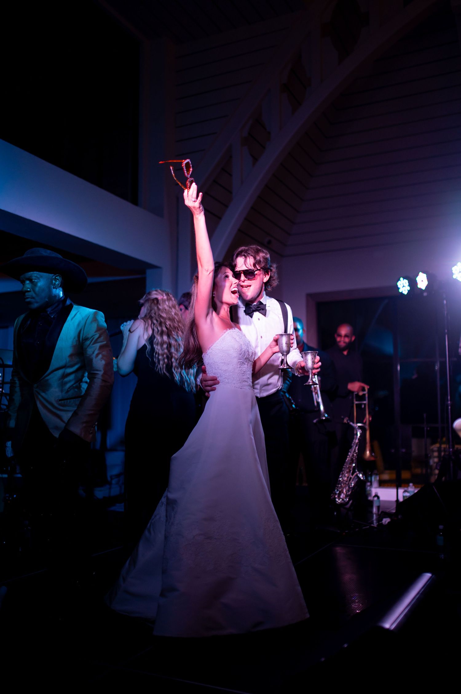 Dramatic silhouettes of wedding dancers performing under blue stage lighting.