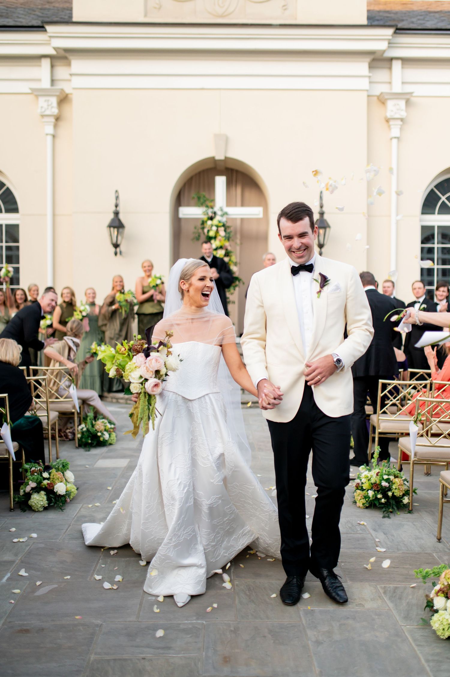 Wedding couple dances while guests celebrate on an outdoor stone patio.