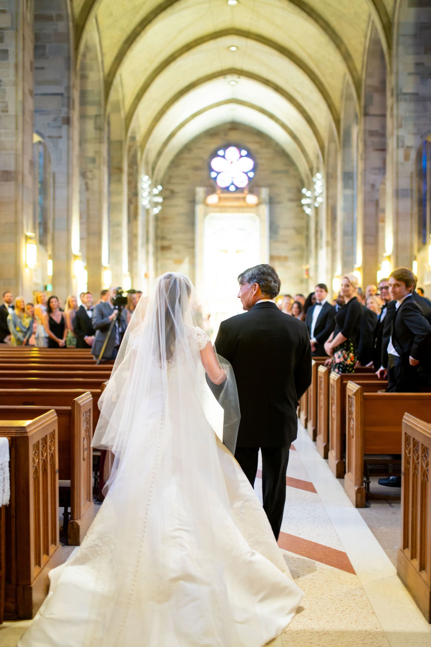 Wedding ceremony procession in a beautiful cathedral with vaulted ceilings and stone columns.