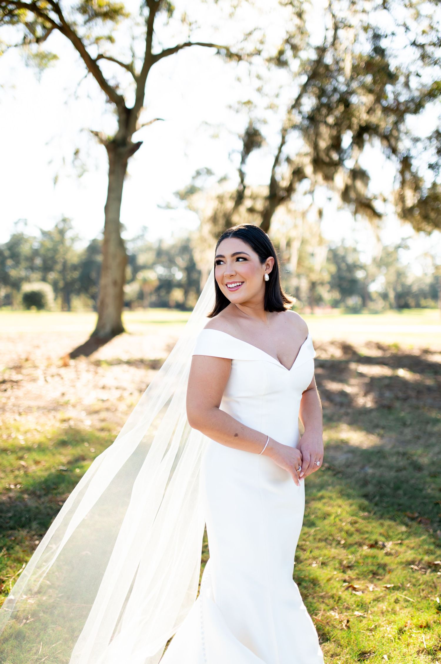 Bride in white dress twirling in outdoor sunlit setting.