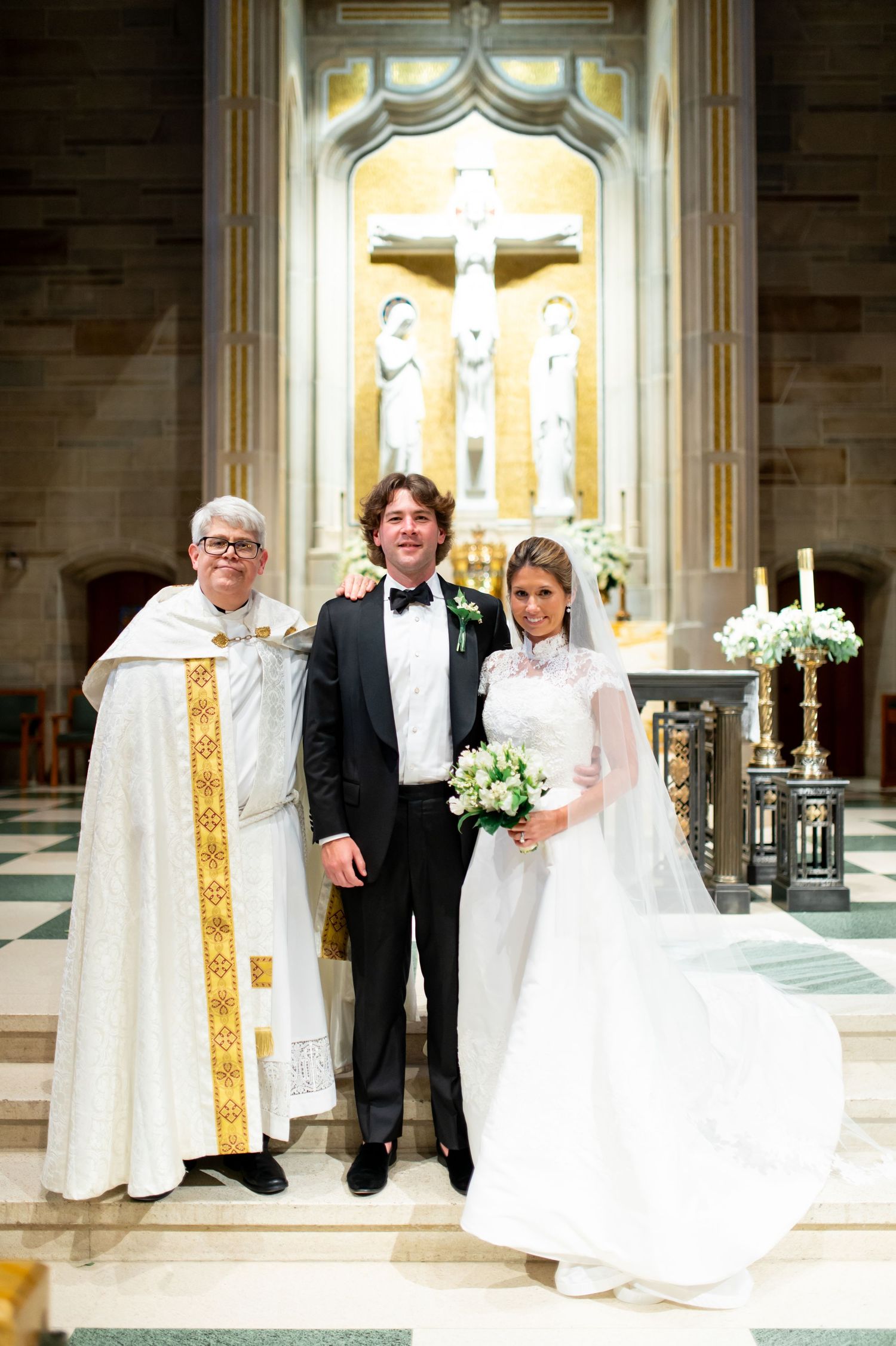 Wedding party gathered at the altar of an elegant cathedral with religious iconography.