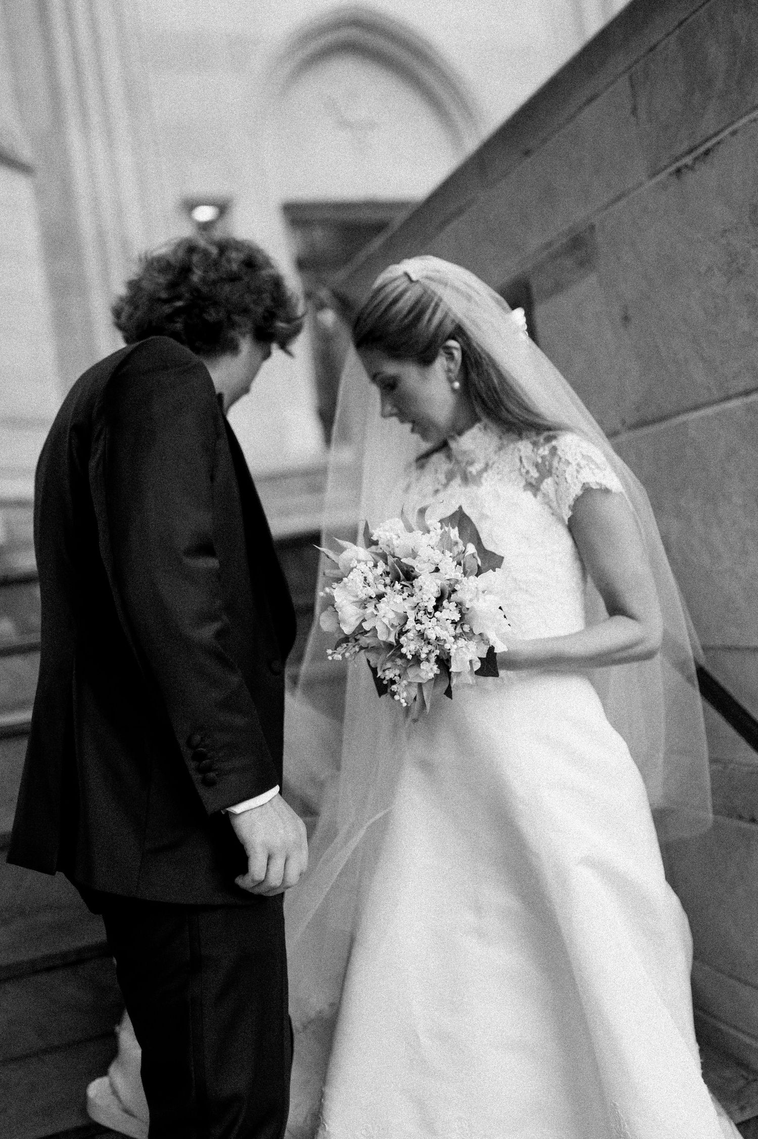 Romantic wedding couple moments captured in black and white on church steps.