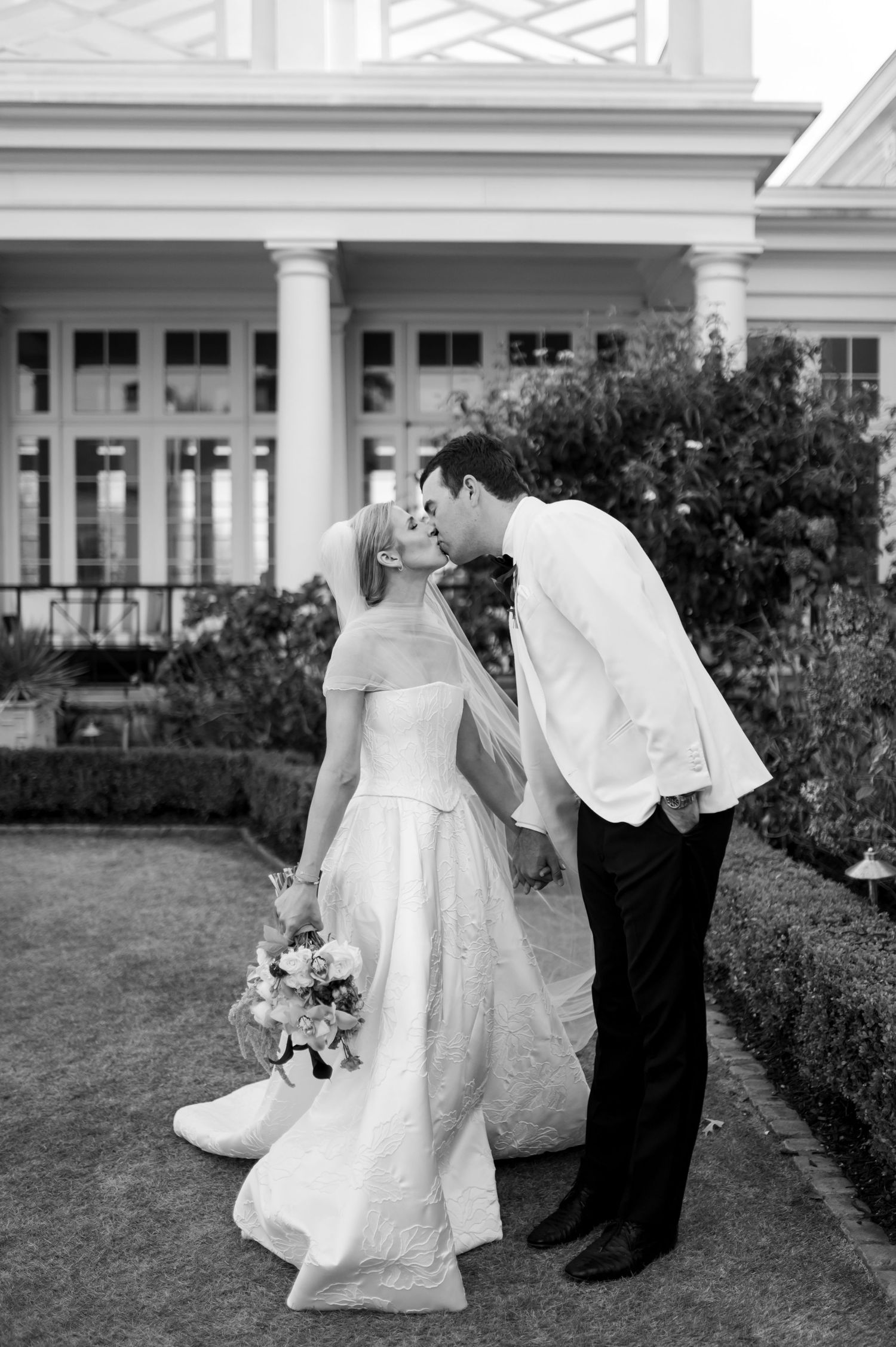 Black and white wedding photos showing couple walking together in formal attire on garden grounds.
