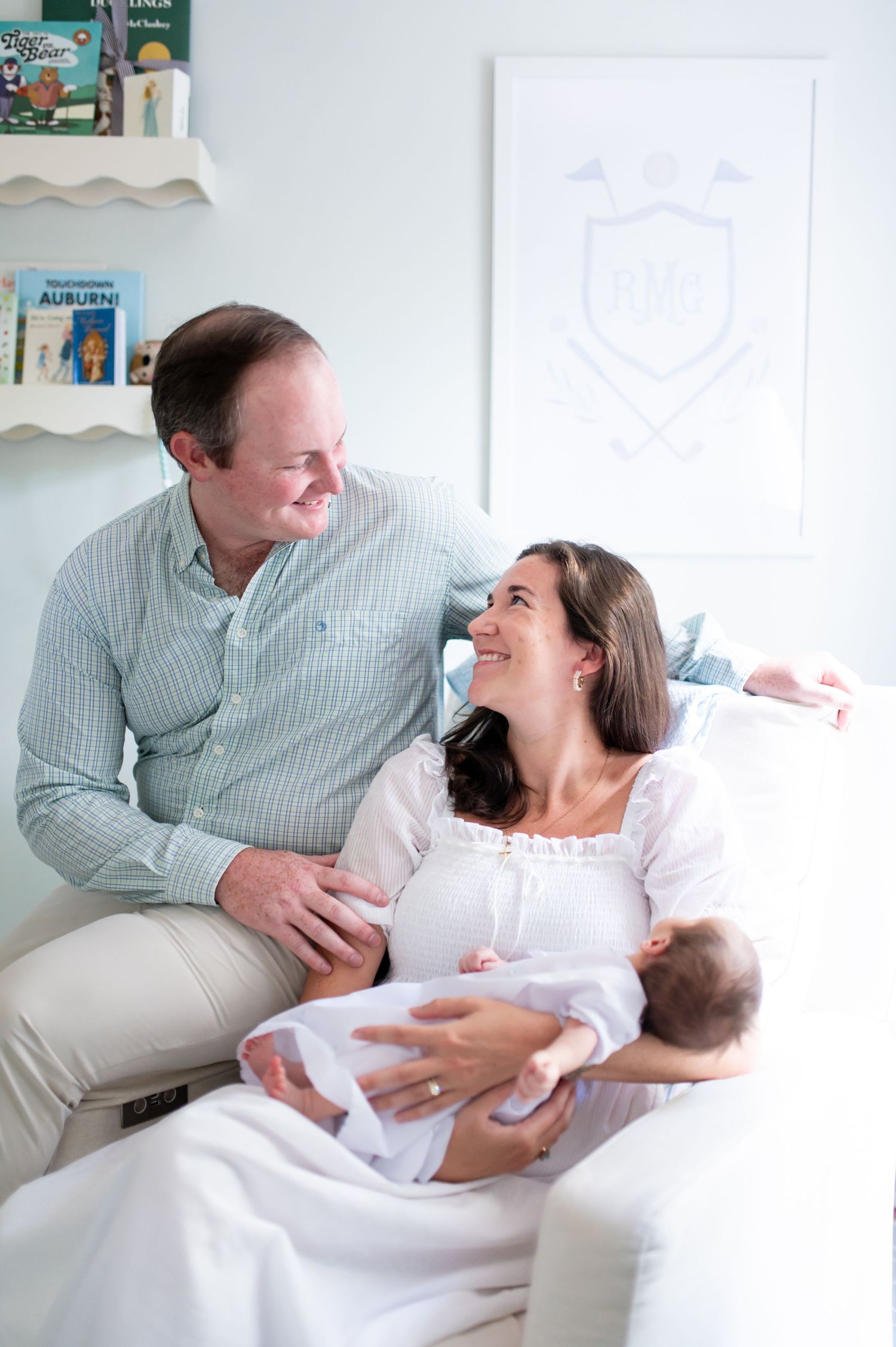 A tender family moment captured in a bright white nursery setting.