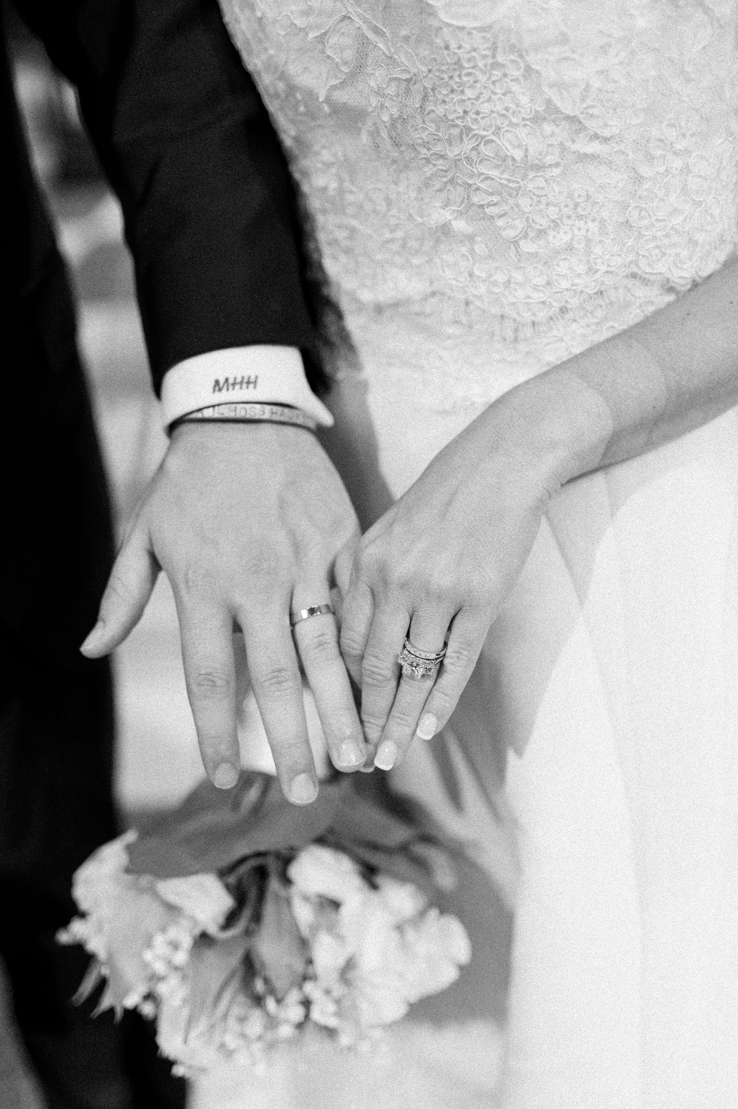 Close-up black and white shots of wedding rings and hands holding flowers.