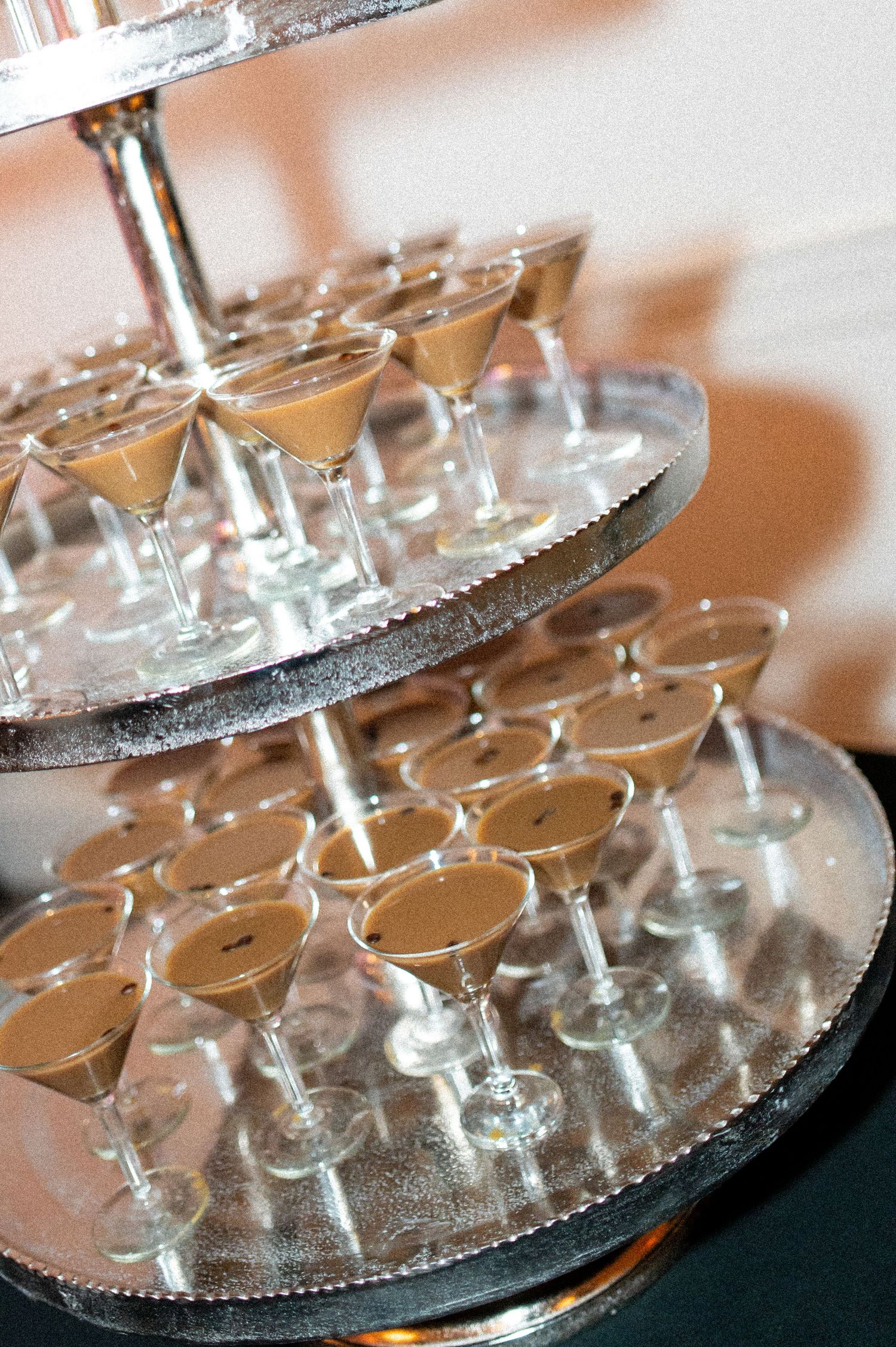 Tiered display of champagne glasses on silver platters at wedding reception.