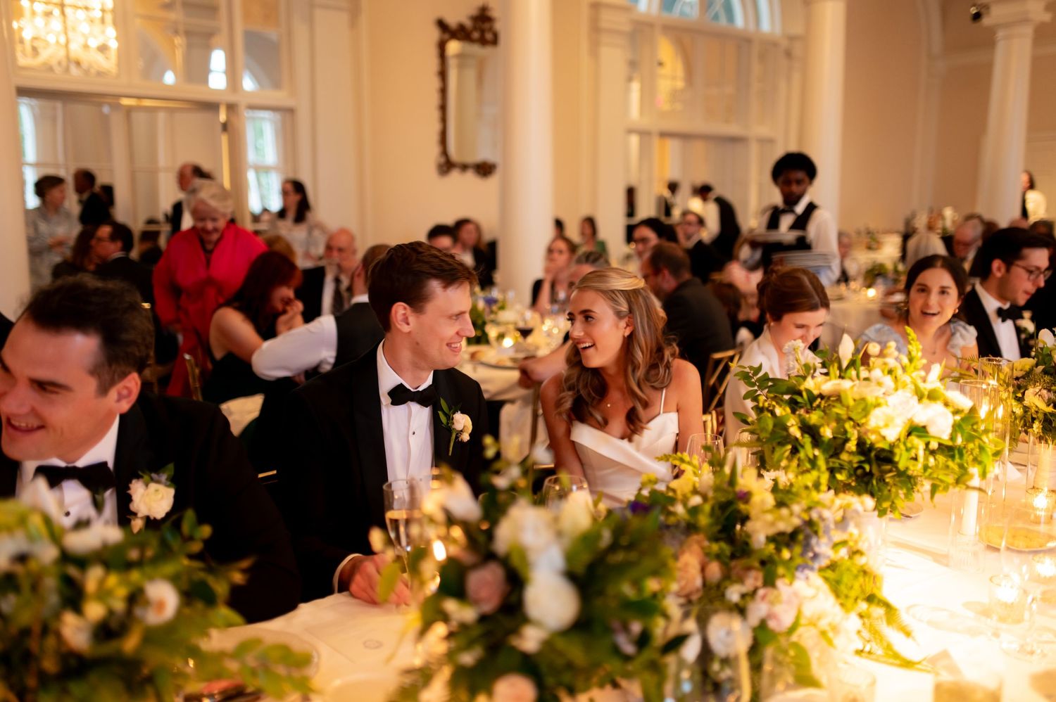 Candlelit wedding reception tables decorated with floral centerpieces in an elegant ballroom.
