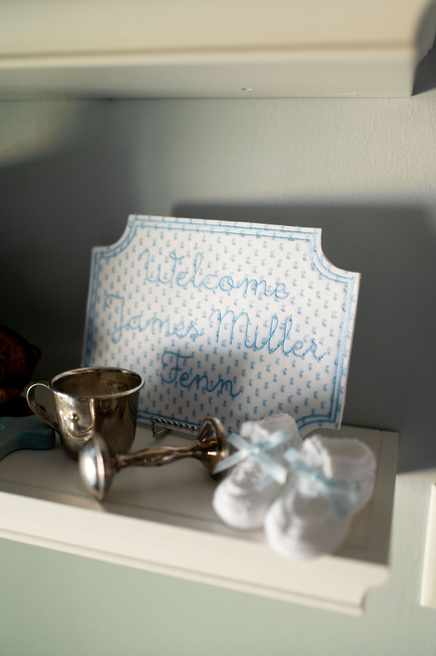 A series of small name cards with blue text displayed on a white shelf in natural lighting.