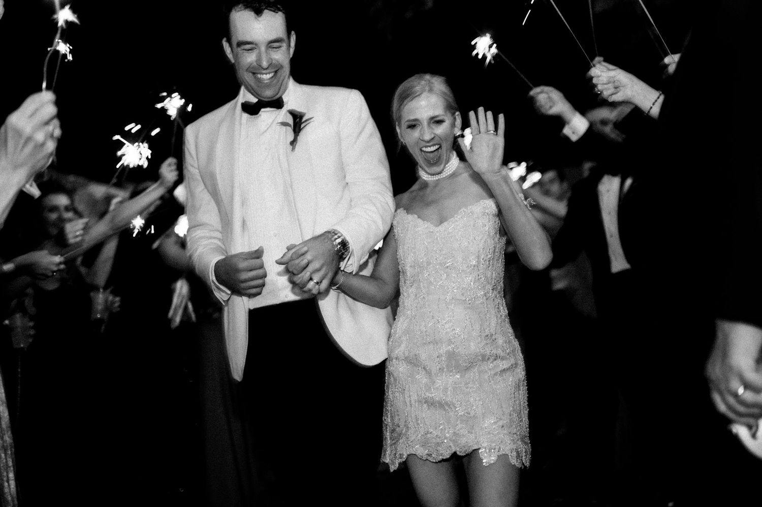 Wedding guests celebrate with sparklers at night during a joyful outdoor send-off celebration.