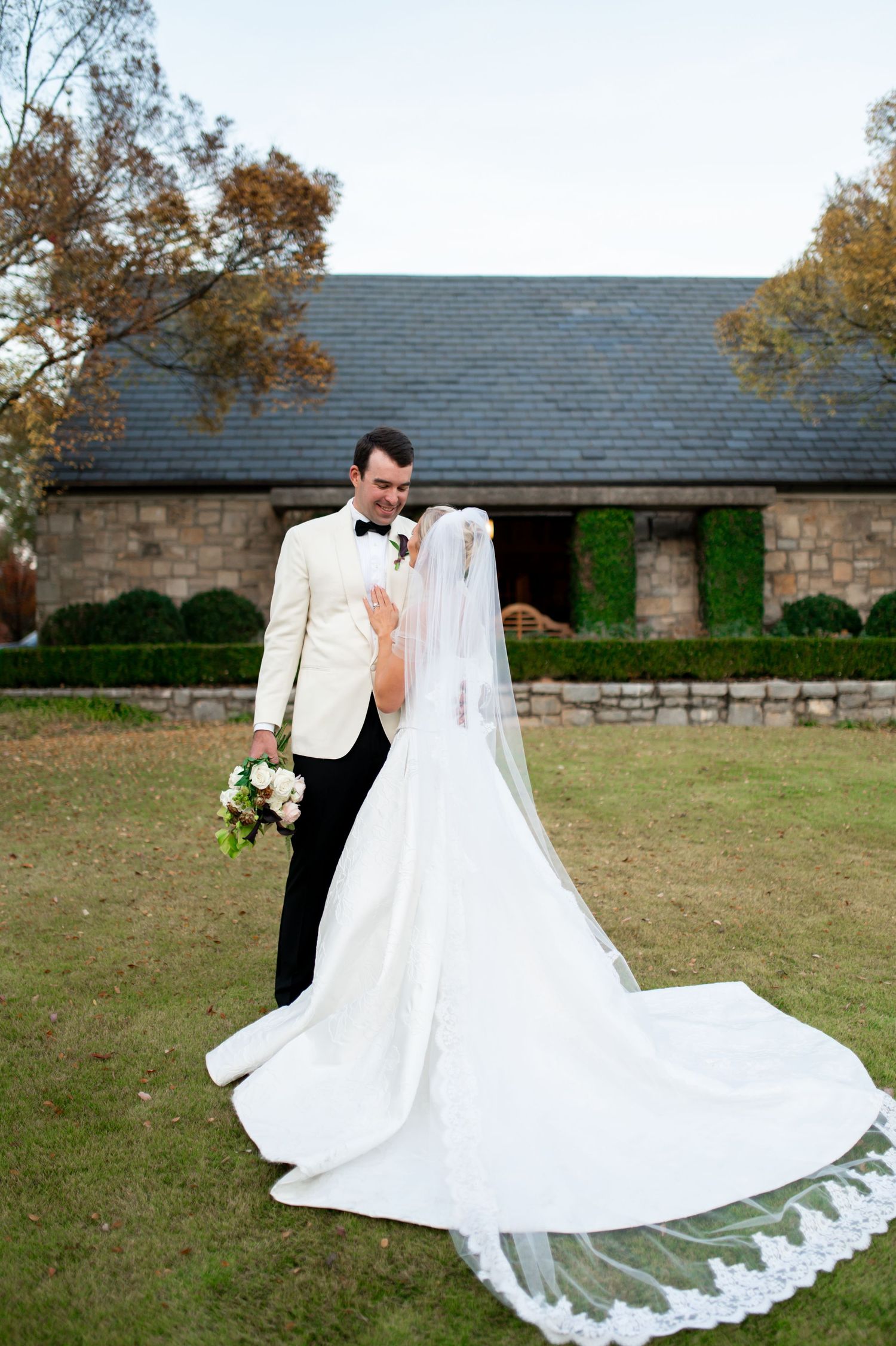 Elegant wedding photos showing flowing white dress against stone building and autumn landscape.