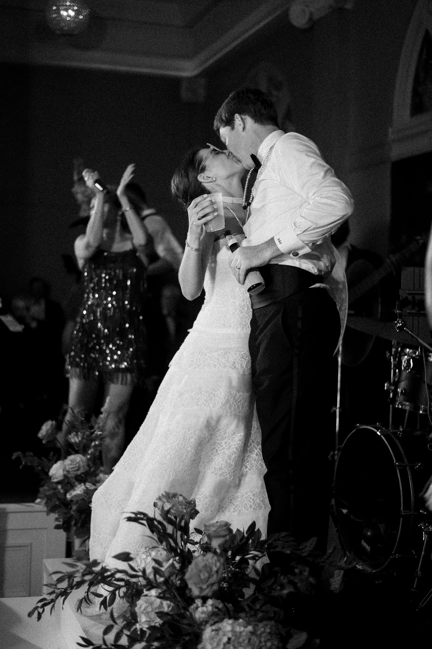 Bride and groom share romantic kiss on dance floor during live band wedding reception.