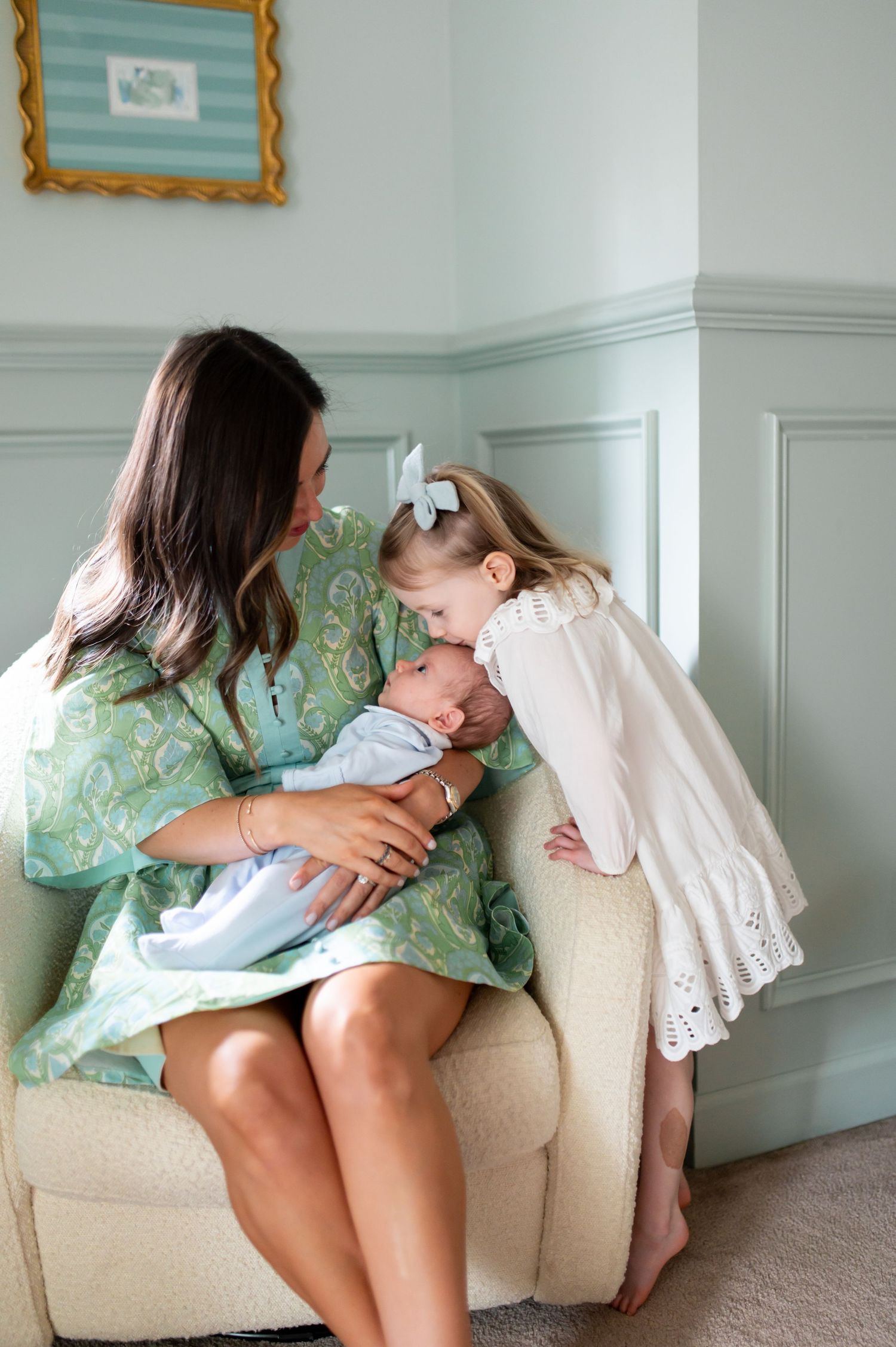 A series of four tender moments showing someone in a mint green dress holding a baby on a beige couch.