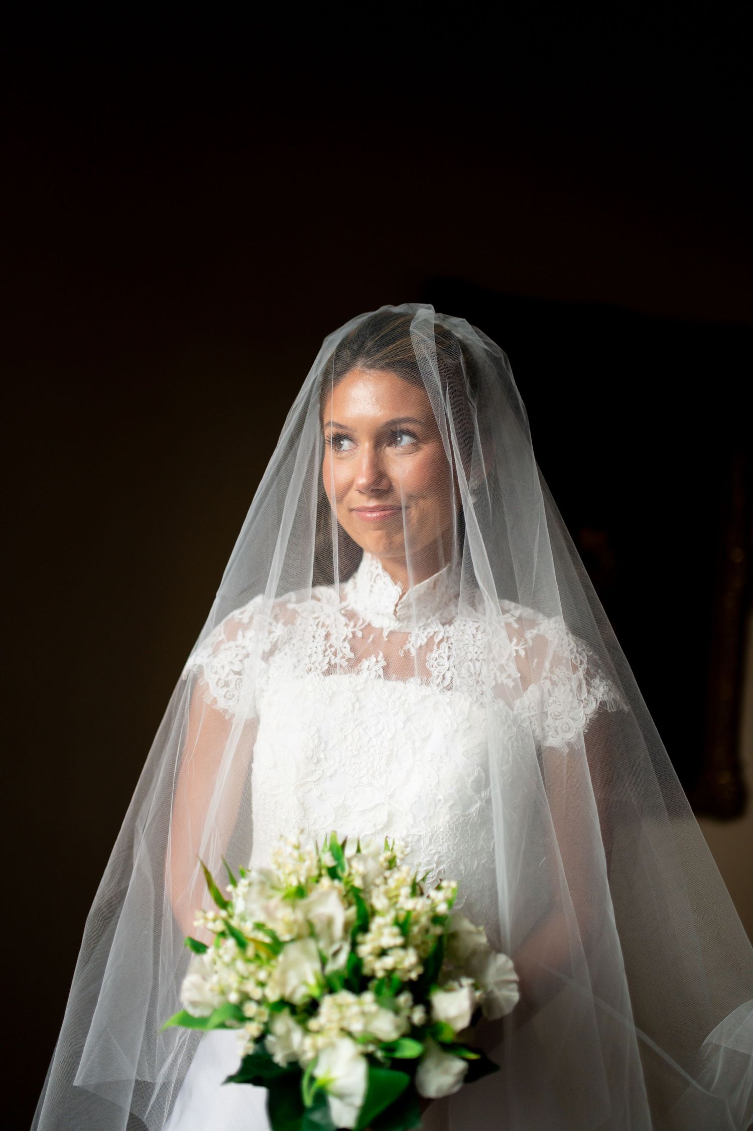 Wedding portrait featuring a white bouquet of flowers and delicate lace veil details.