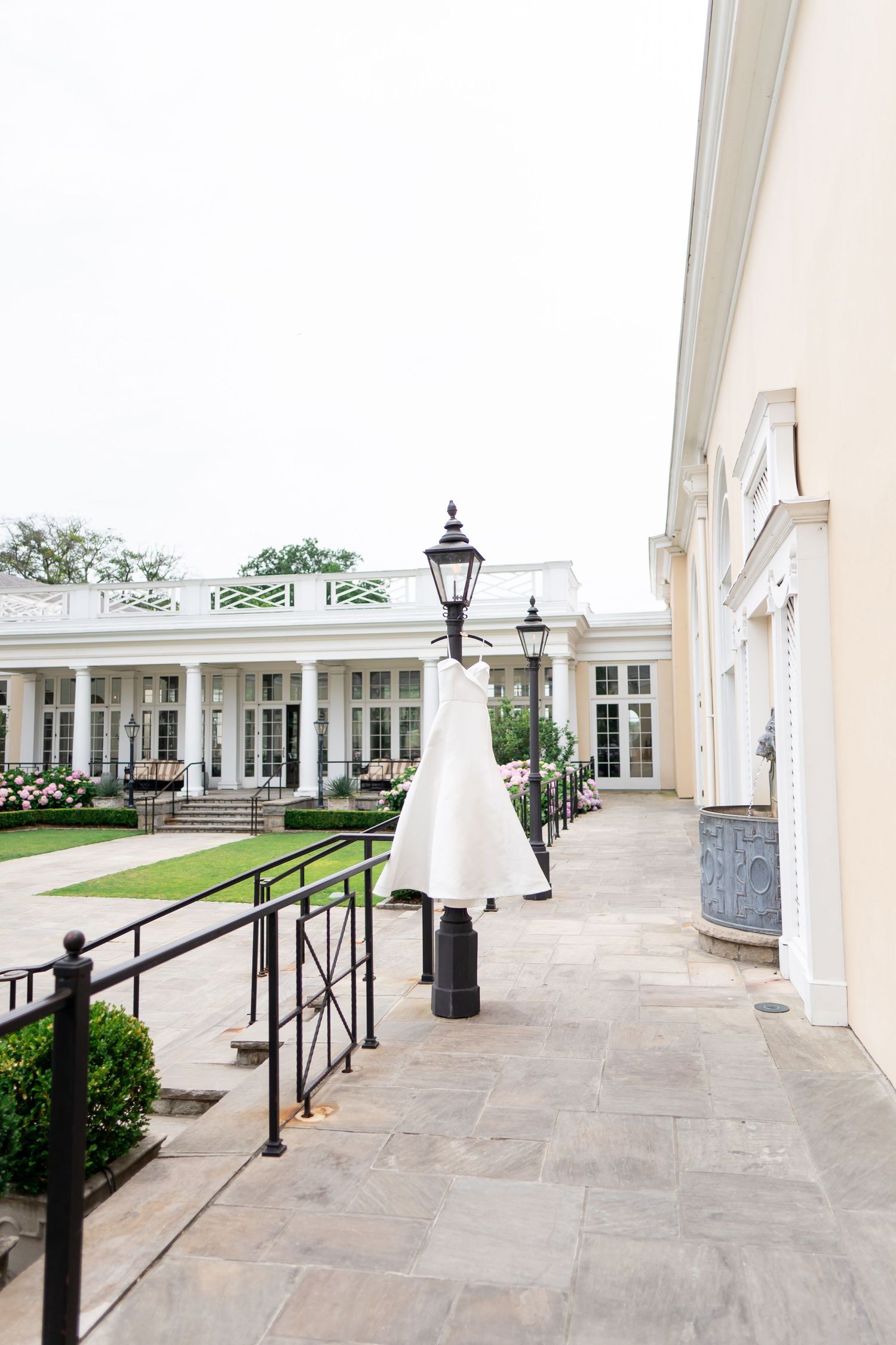 White columned portico with stone flooring and black iron railings at an elegant venue.