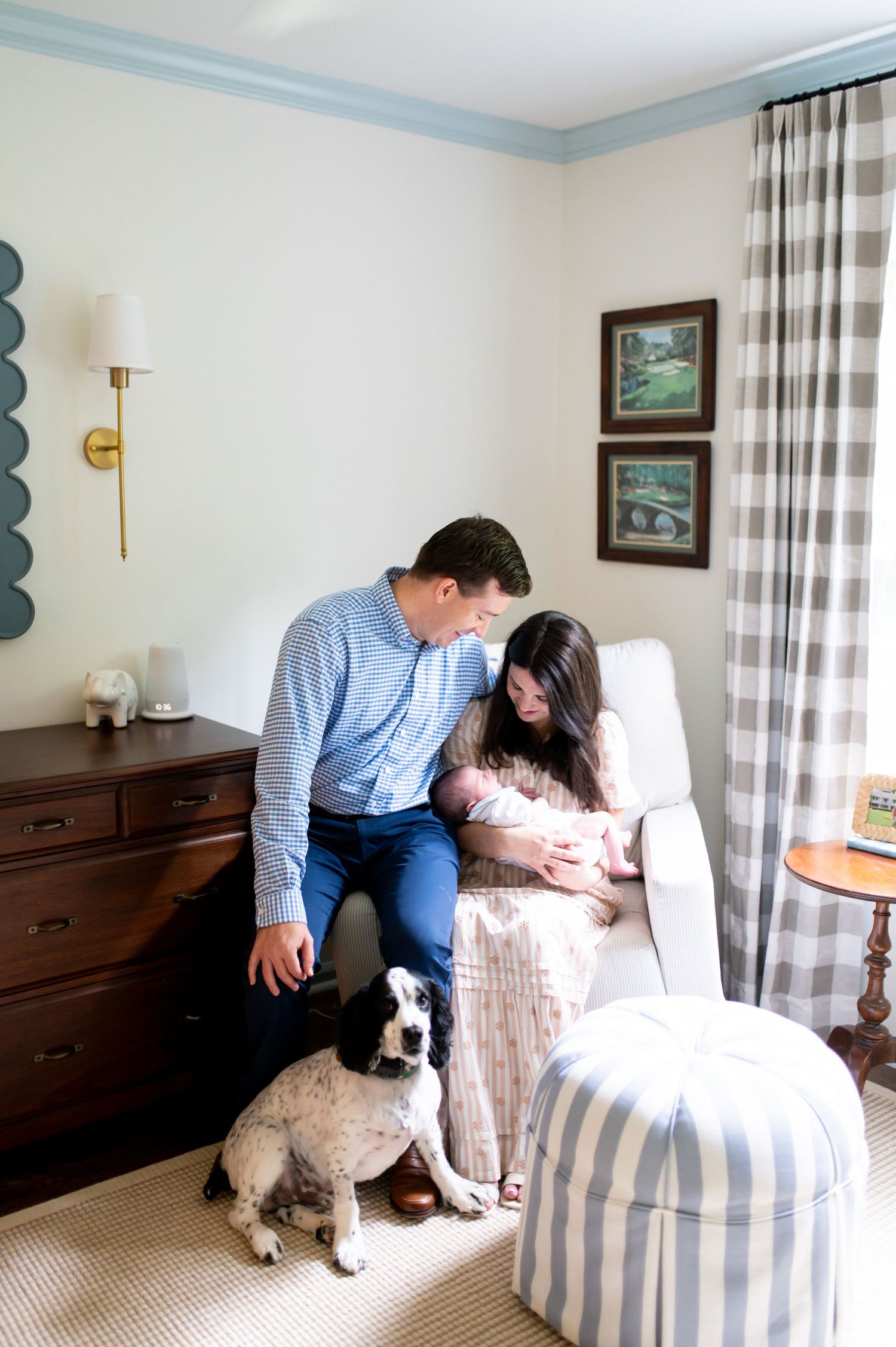 A cozy nursery scene with striped curtains, a white armchair, and a small dog.