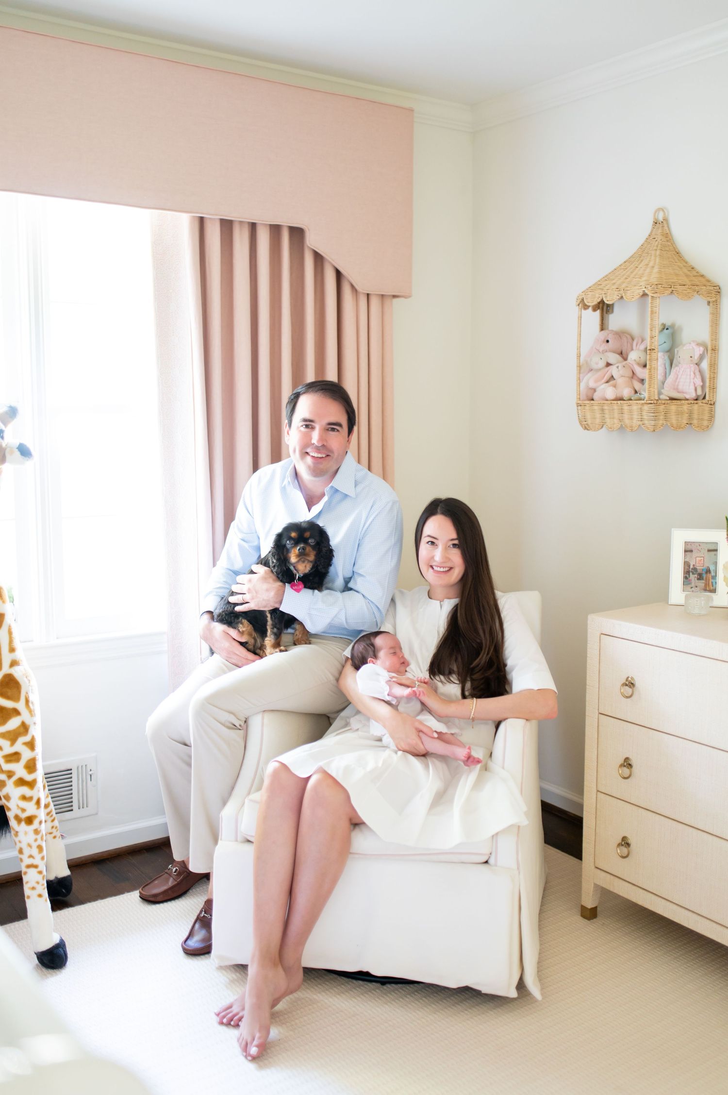 Lifestyle family photos in a neutral nursery with white furniture and pink accents.