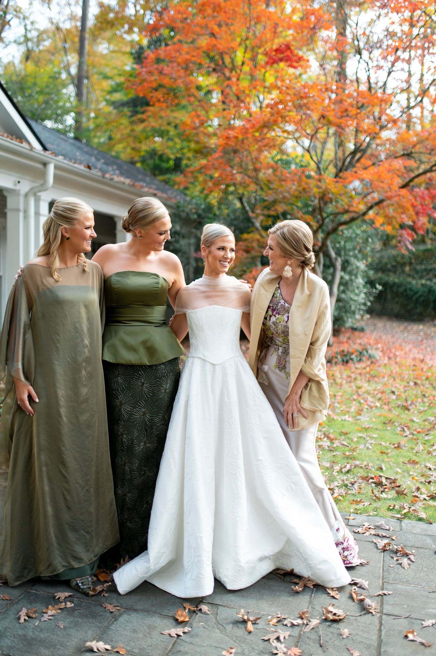 Wedding party in elegant evening wear poses against autumn scenery.