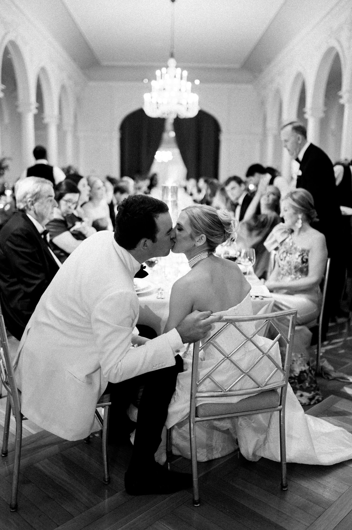 Wedding guests relax in elegant chairs during the reception in a grand ballroom.