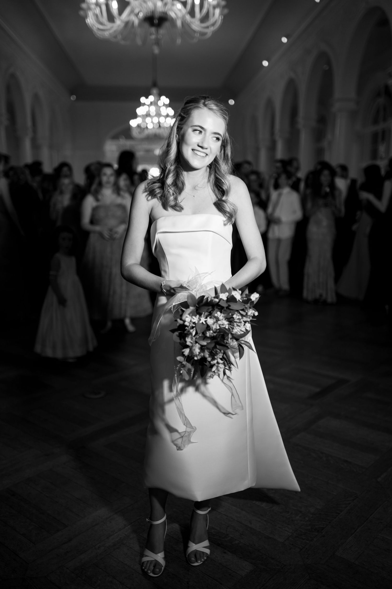 Formal event in grand ballroom with chandeliers and elegant decor.