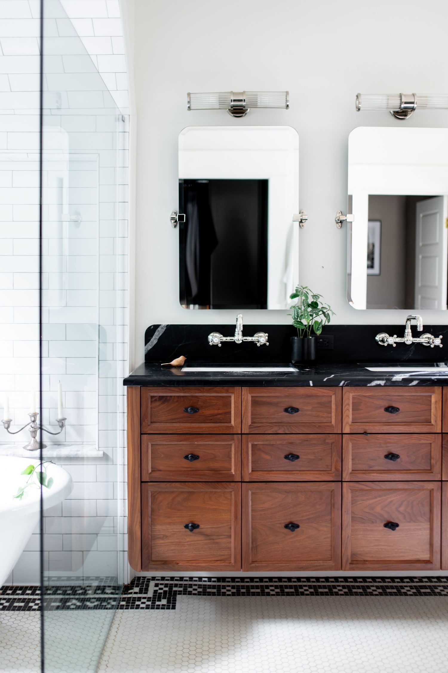 Luxurious bathroom featuring a long wooden vanity with black countertop and multiple sinks against white walls.