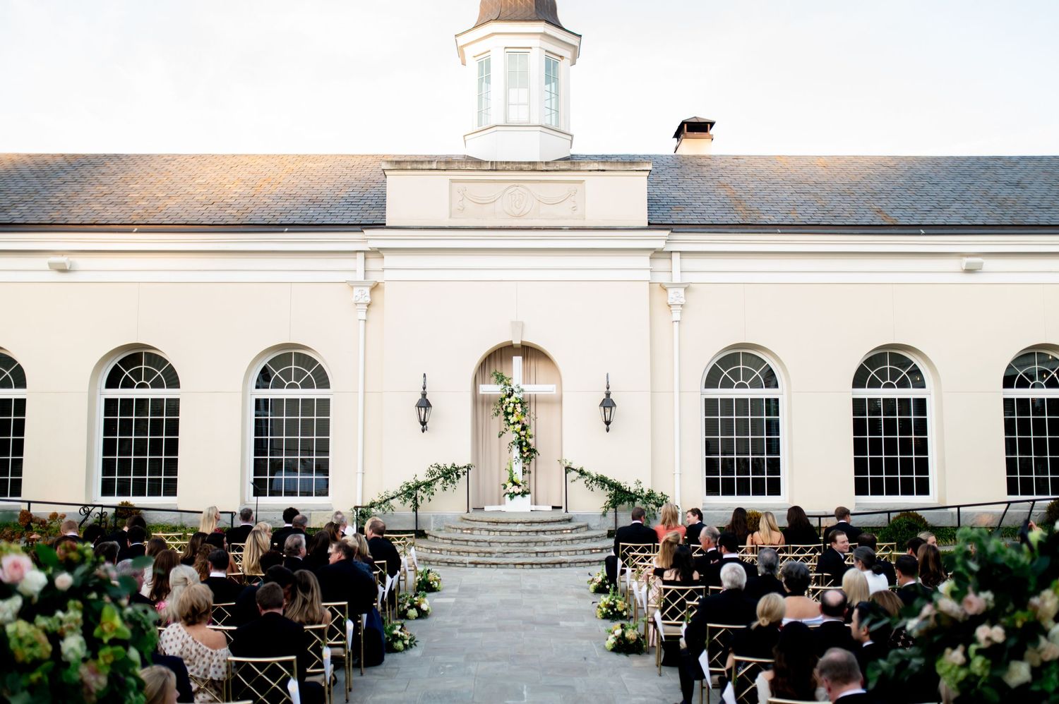 Exterior view of an elegant white wedding venue with colonial architecture and arched windows.