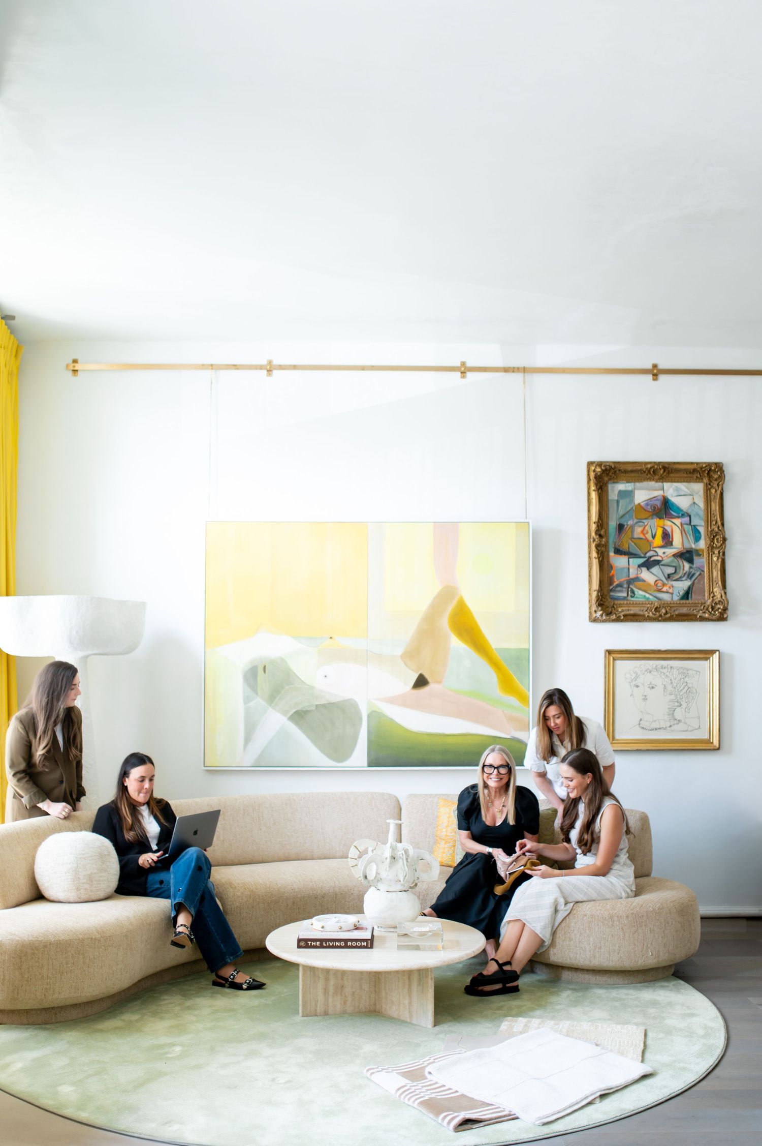 A bright modern lounge area features curved seating and abstract wall art in a minimalist setting.