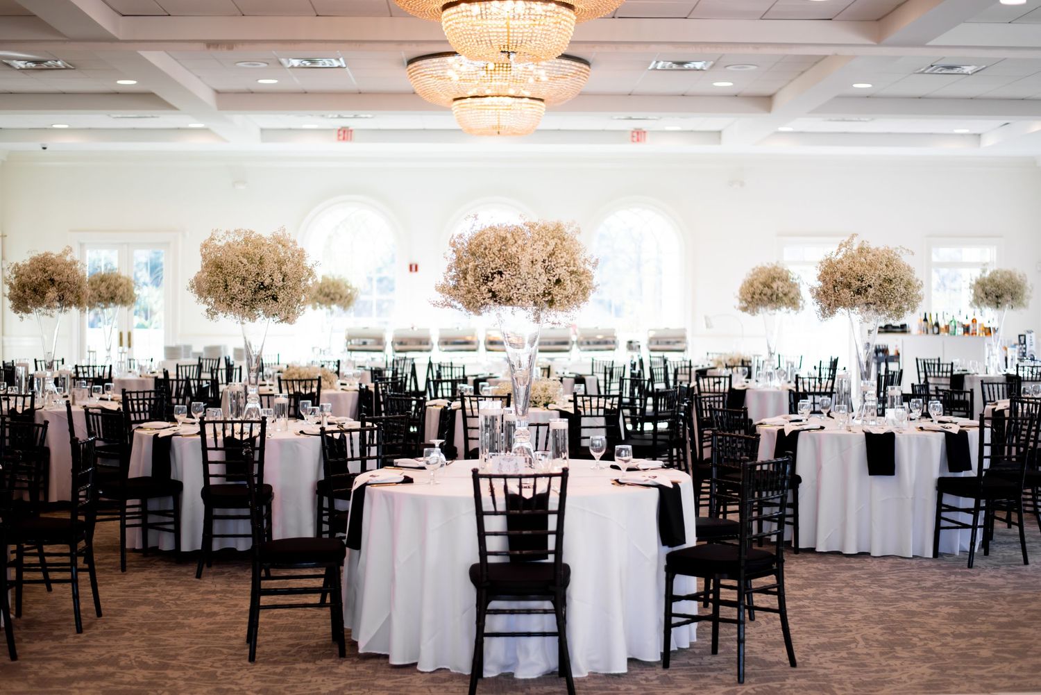 Elegant wedding reception venue with crystal chandeliers and tables set with white linens.