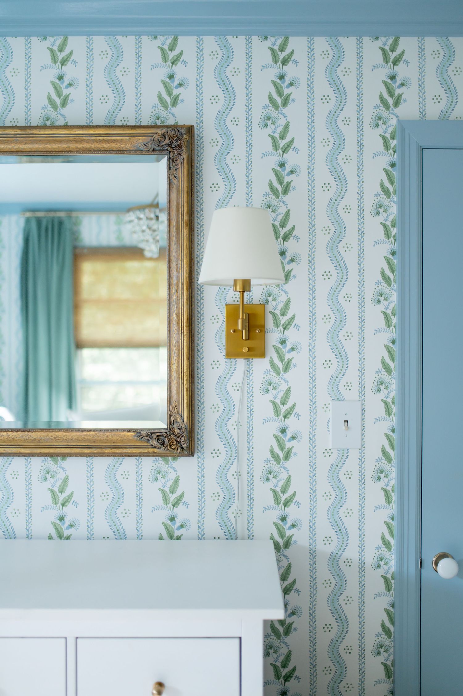 Light blue and white striped wallpaper with delicate green leaf pattern creates a vintage-inspired interior design aesthetic.