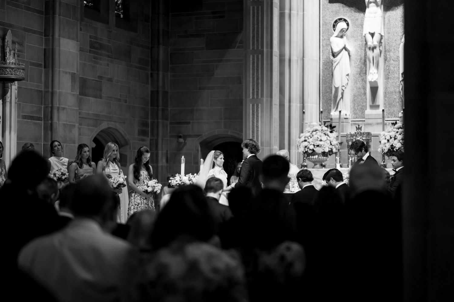 Silhouetted wedding ceremony taking place in a historic church with dramatic lighting.