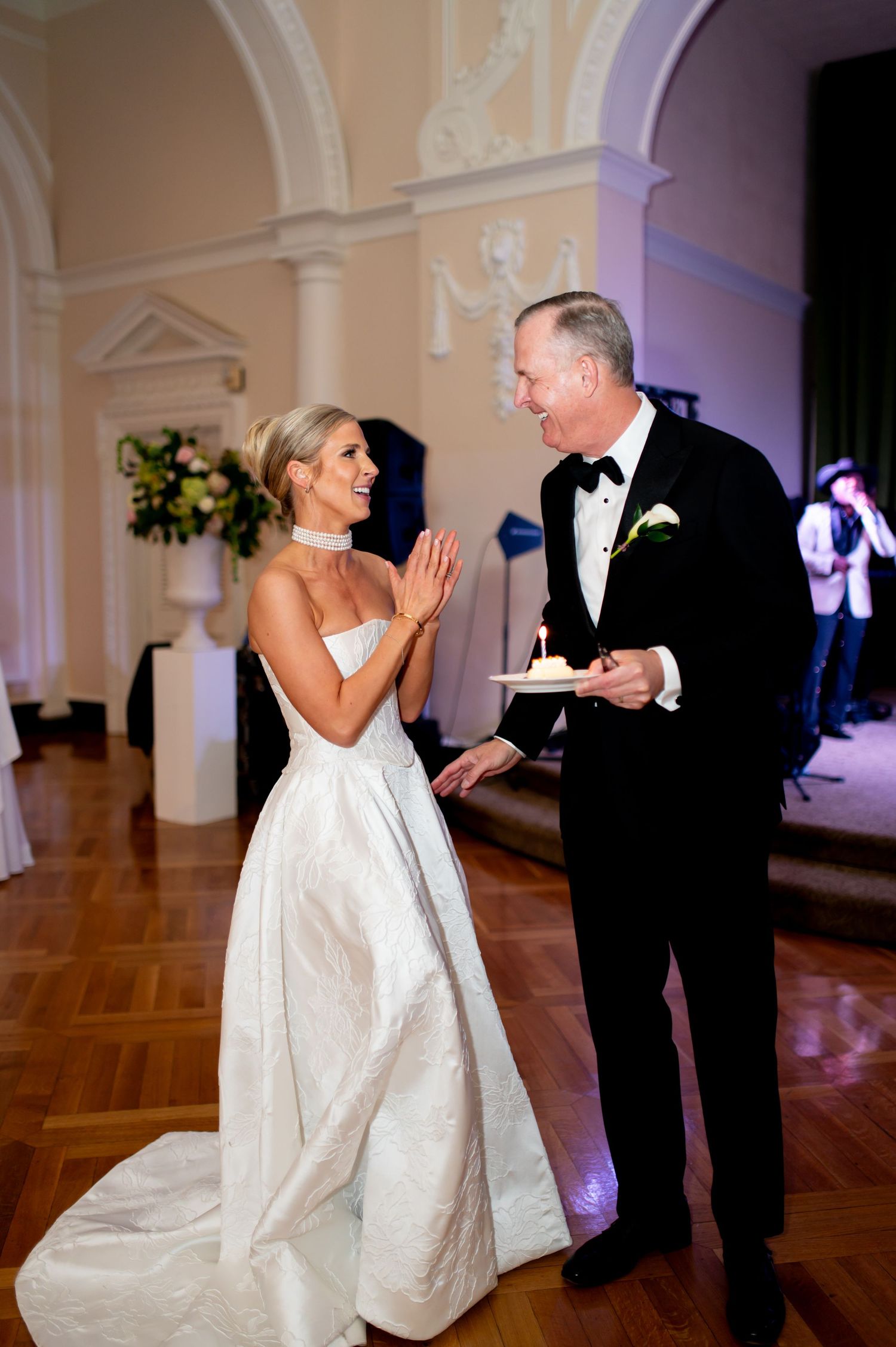 A couple shares a playful moment during their wedding dance in an elegant ballroom setting.