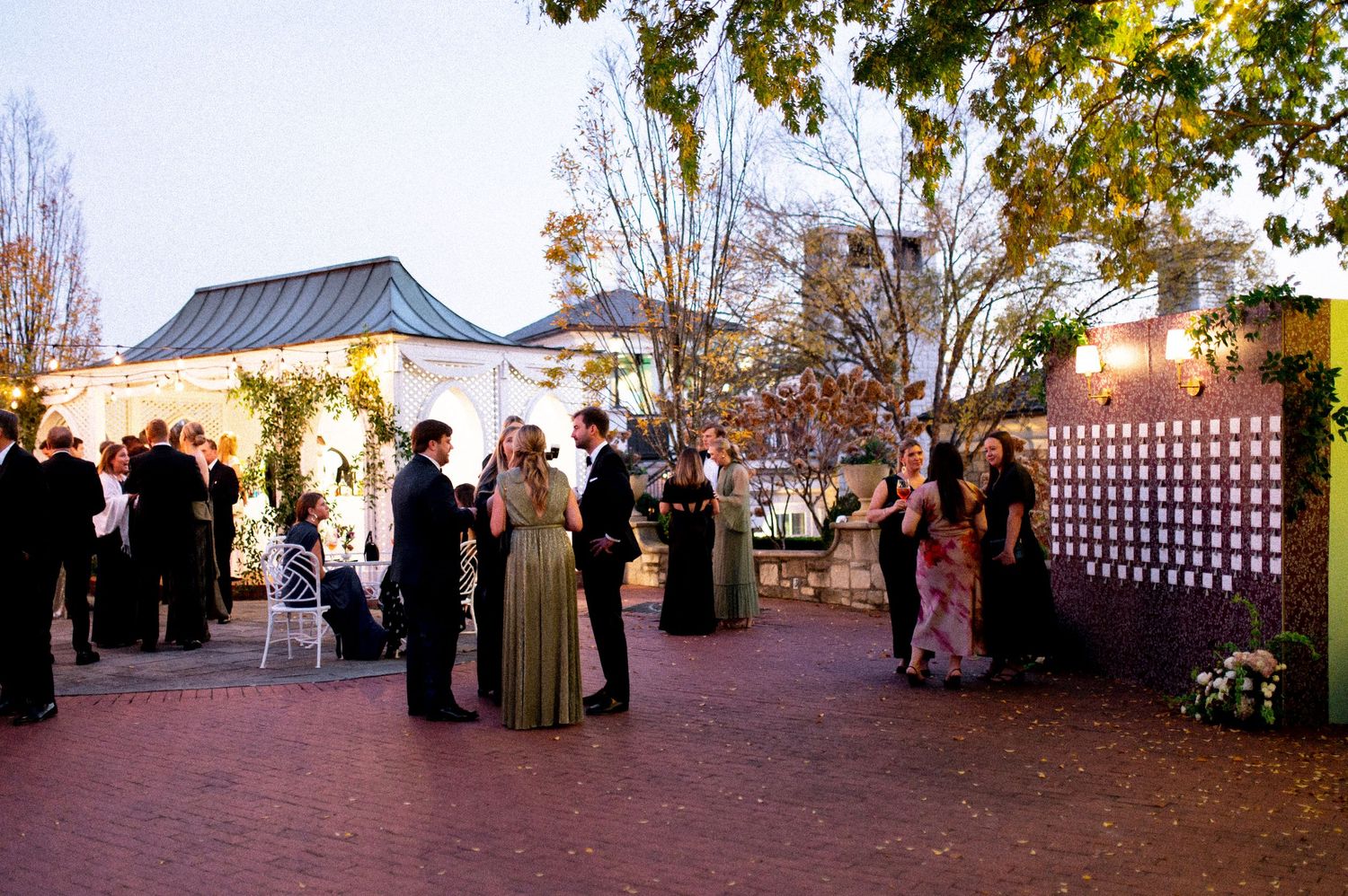 Elegant outdoor wedding reception setup at dusk with string lights and white decor.