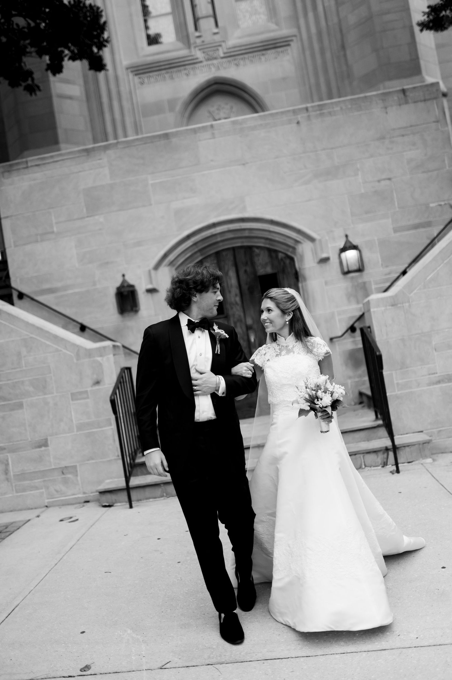 Black and white wedding photos showing playful moments on church steps.