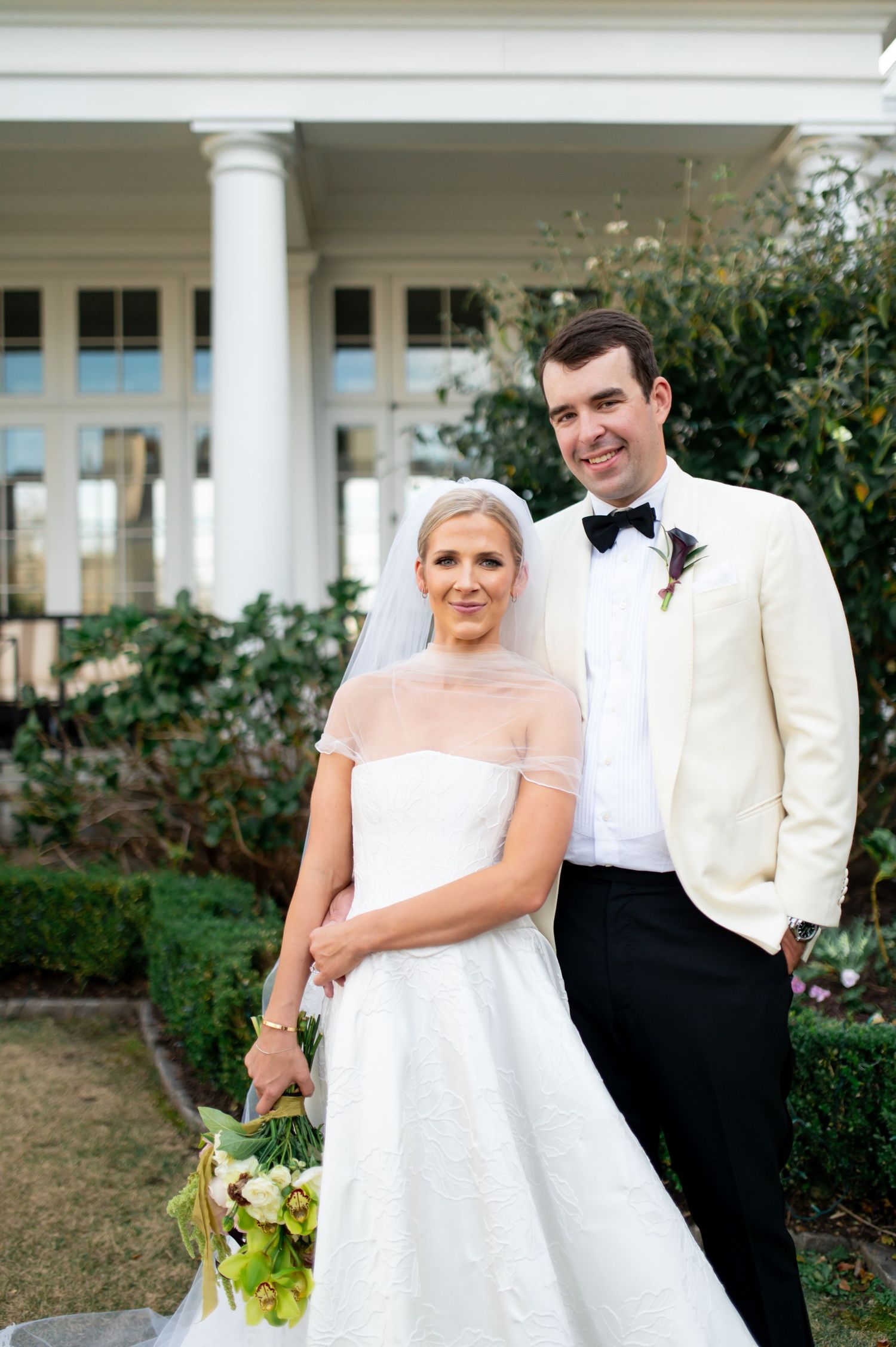 Joyful wedding portraits captured in front of a southern-style mansion with white columns.