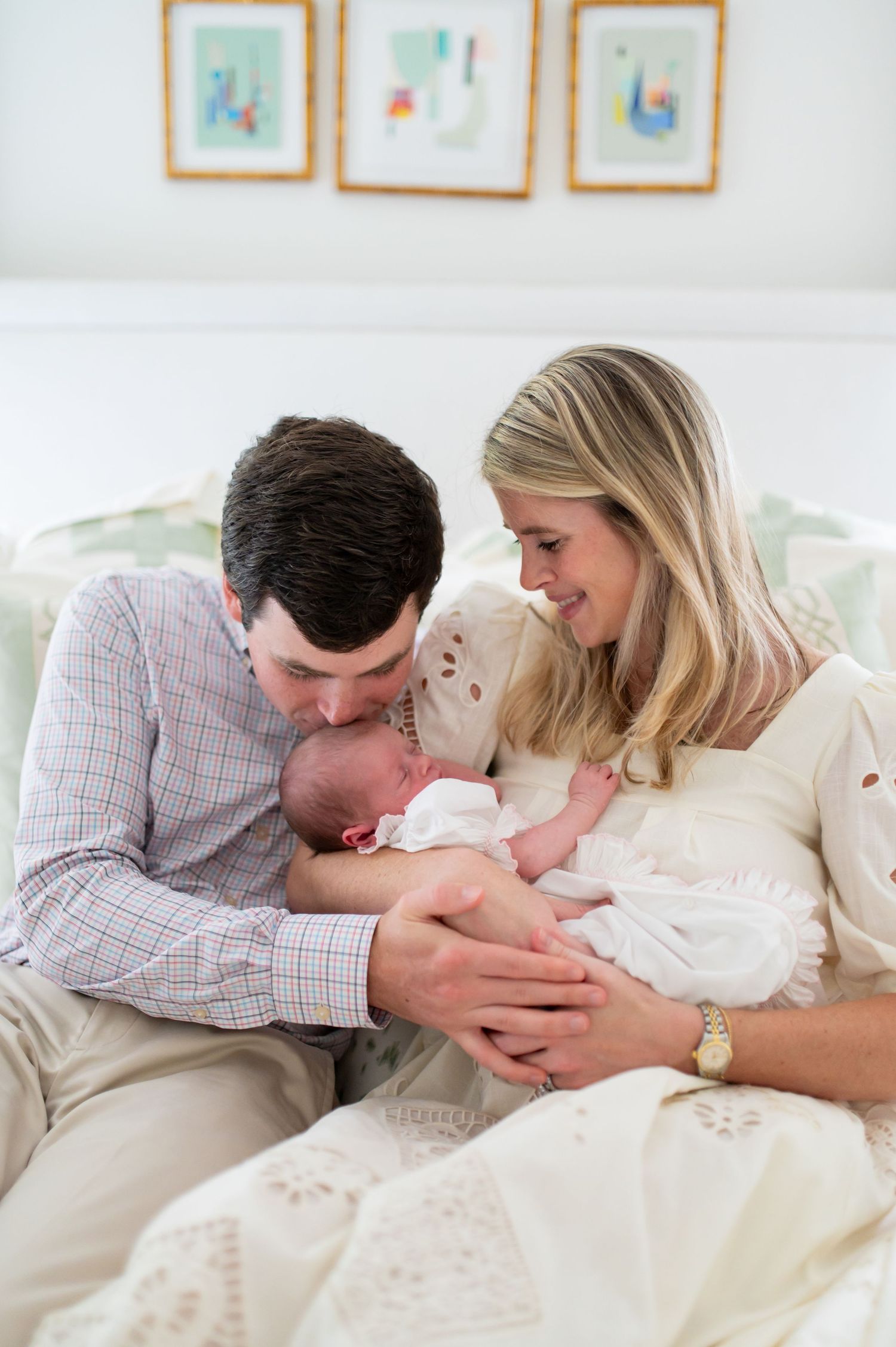 A loving family shares tender moments together while relaxing on a white couch.