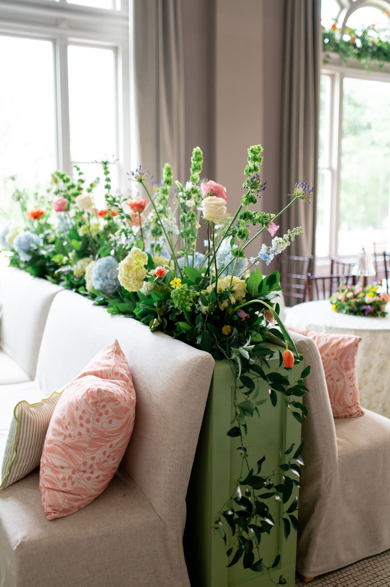Elegant wedding floral arrangement with pastel blooms and greenery cascading over sofa back.
