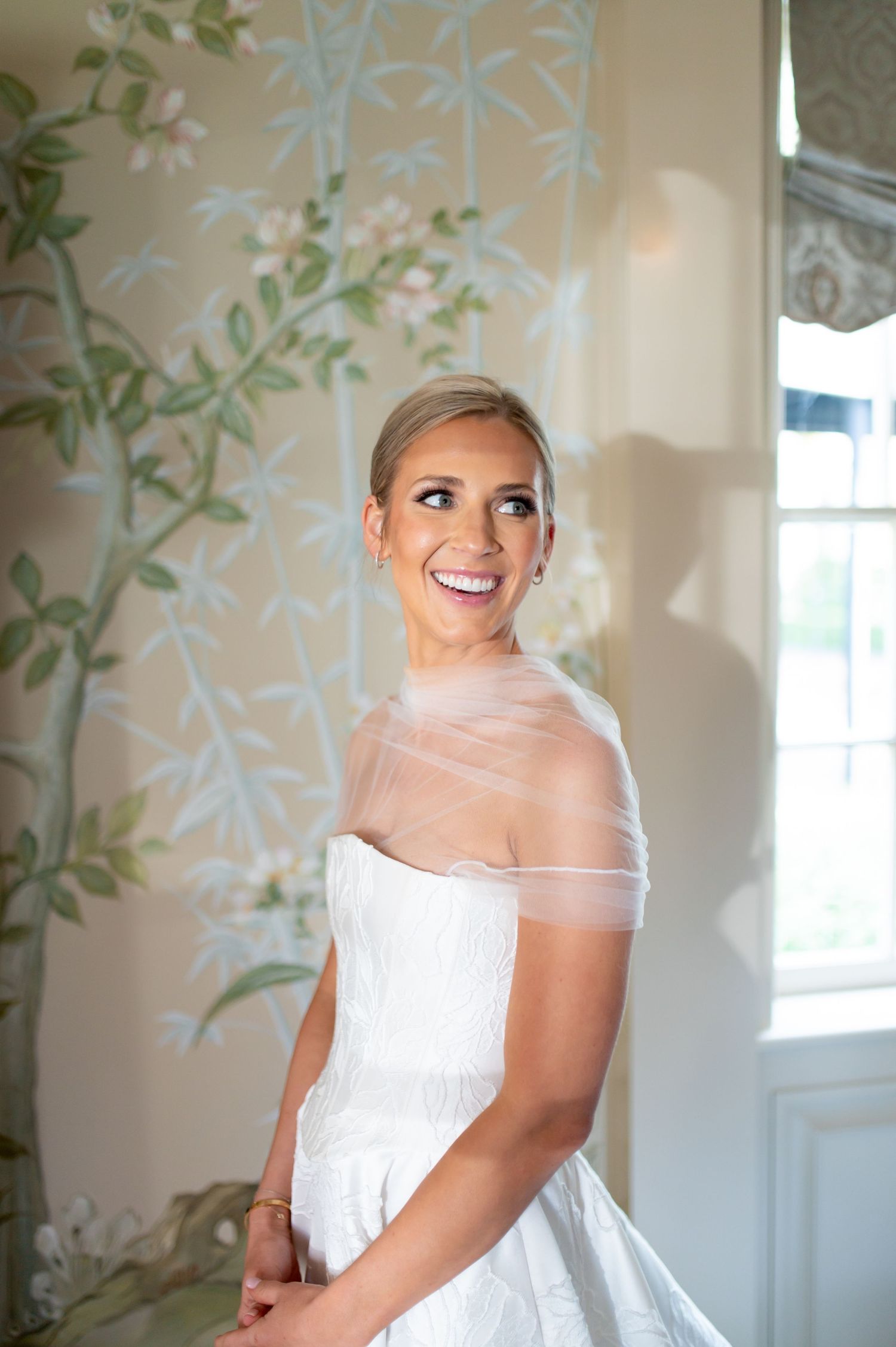 Joyful bridal portraits in an elegant room with soft lighting and floral wall details.