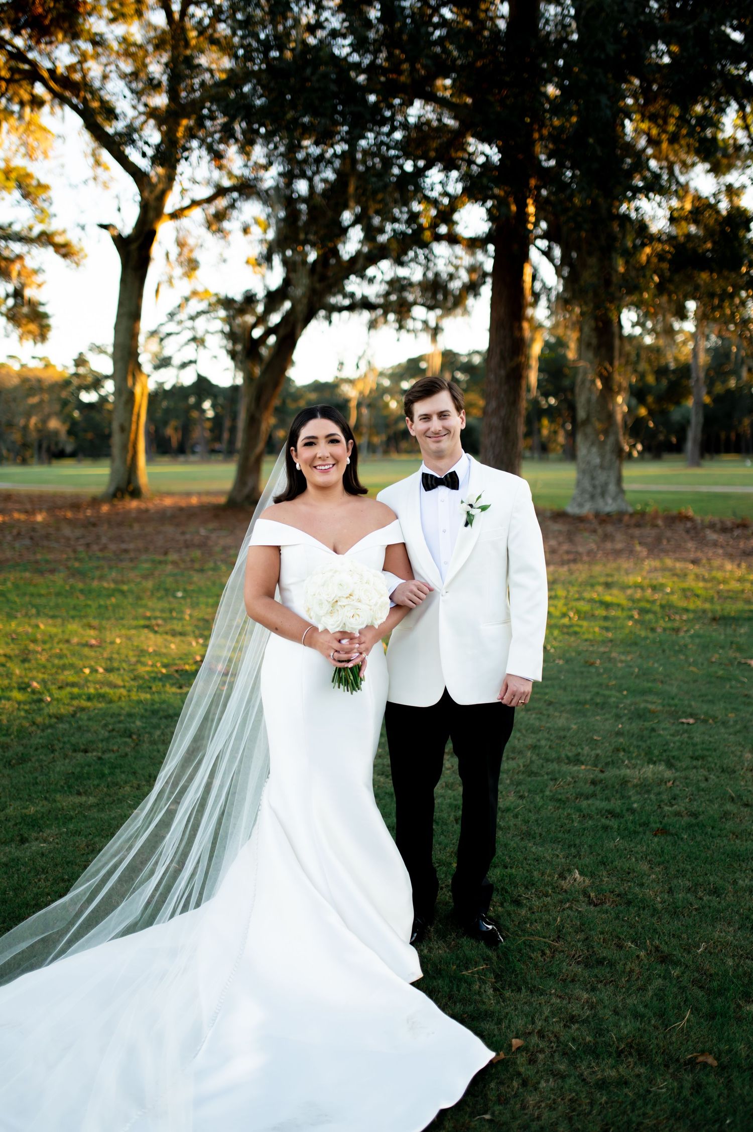 Romantic wedding portraits with flowing white dress and veil against autumn trees.