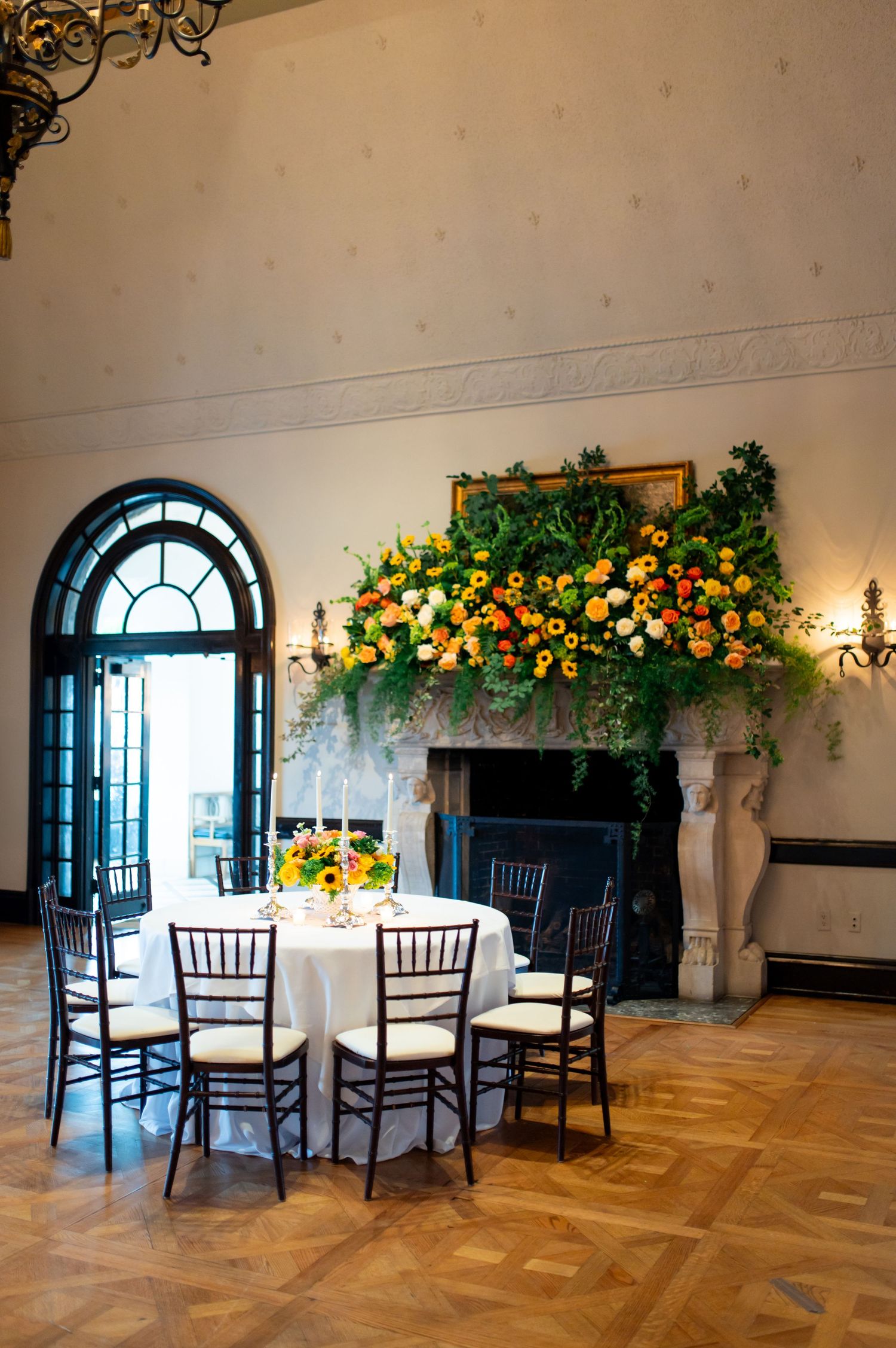 Elegant reception room with dark wood chairs and floral arrangements hanging above tables.