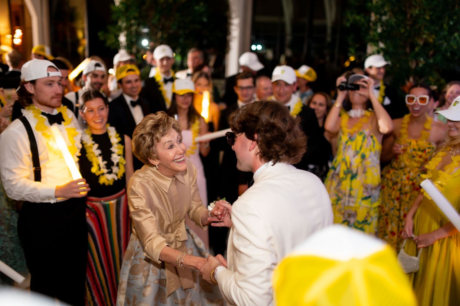 Lively wedding party scene with guests dancing and celebrating in colorful attire.