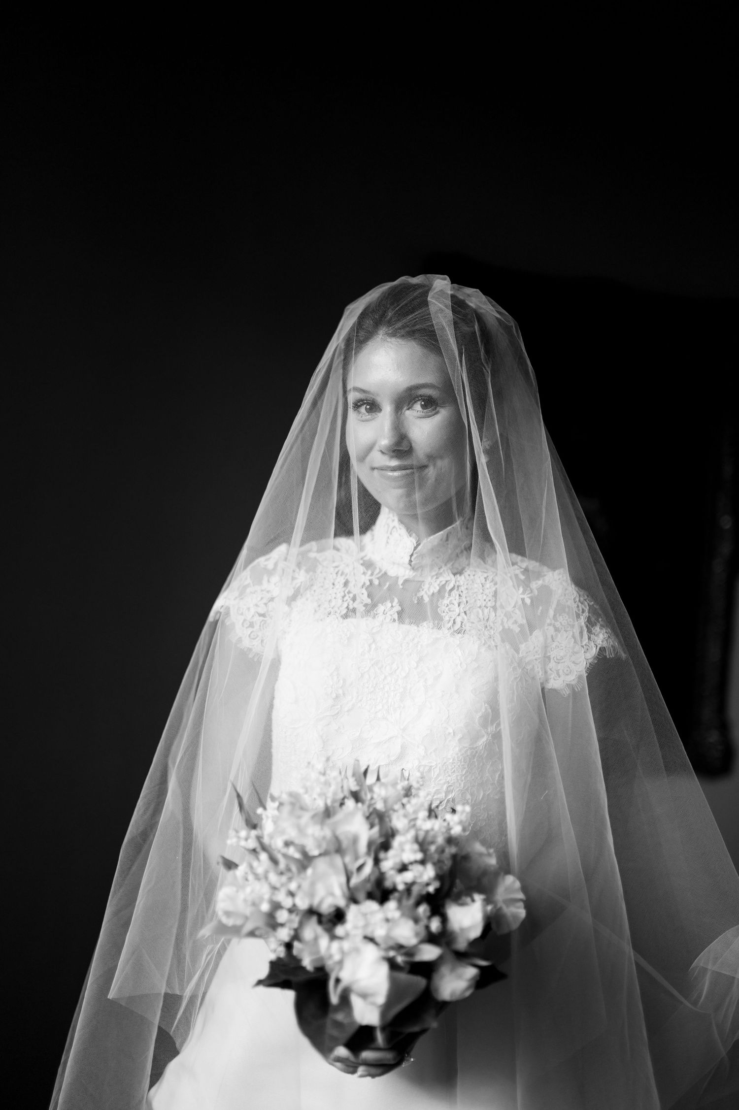 Elegant white bridal bouquet with lace veil details captured in black and white.