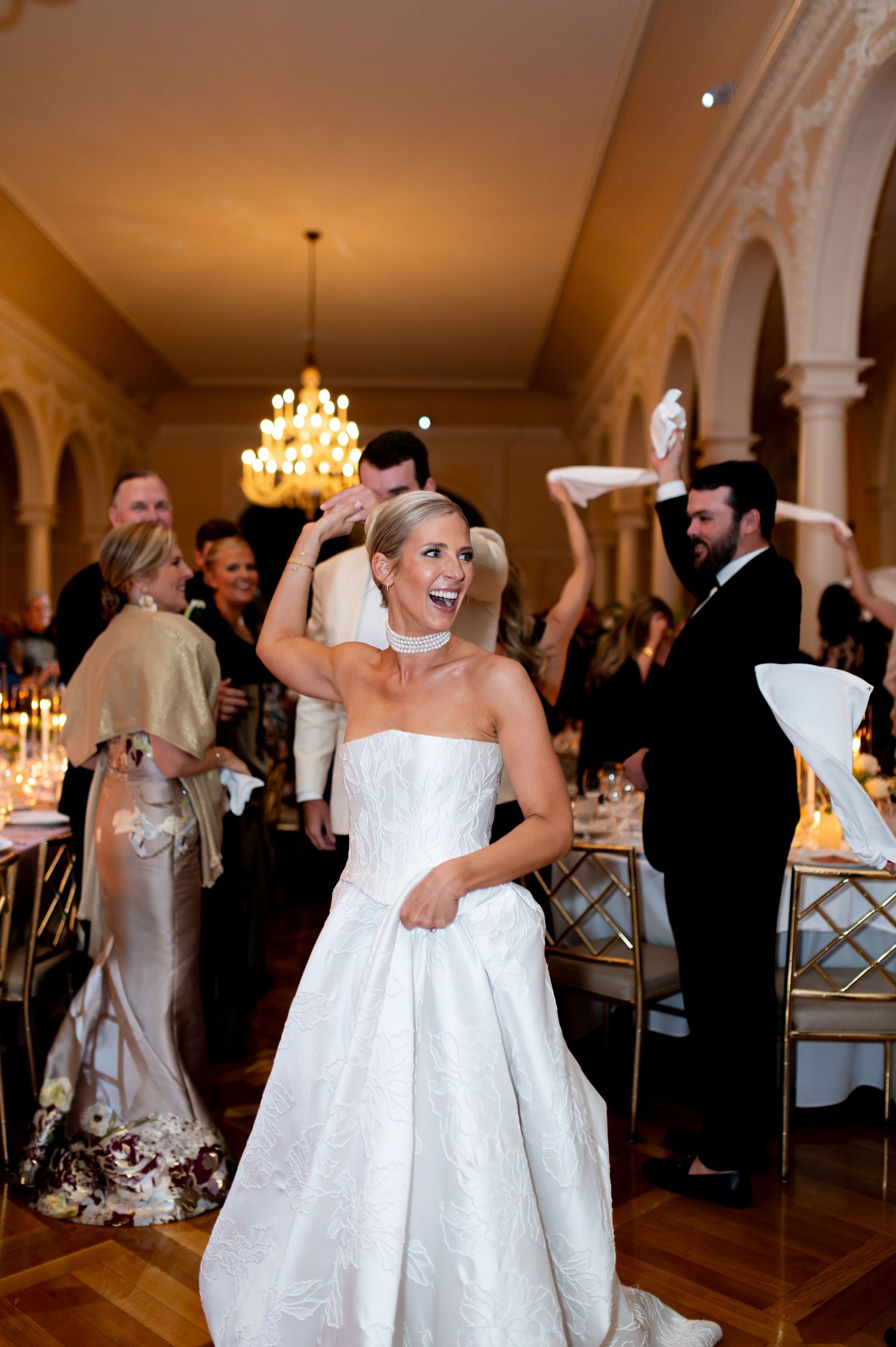 Joyful dancing and celebration during a wedding reception in an elegant white ballroom.