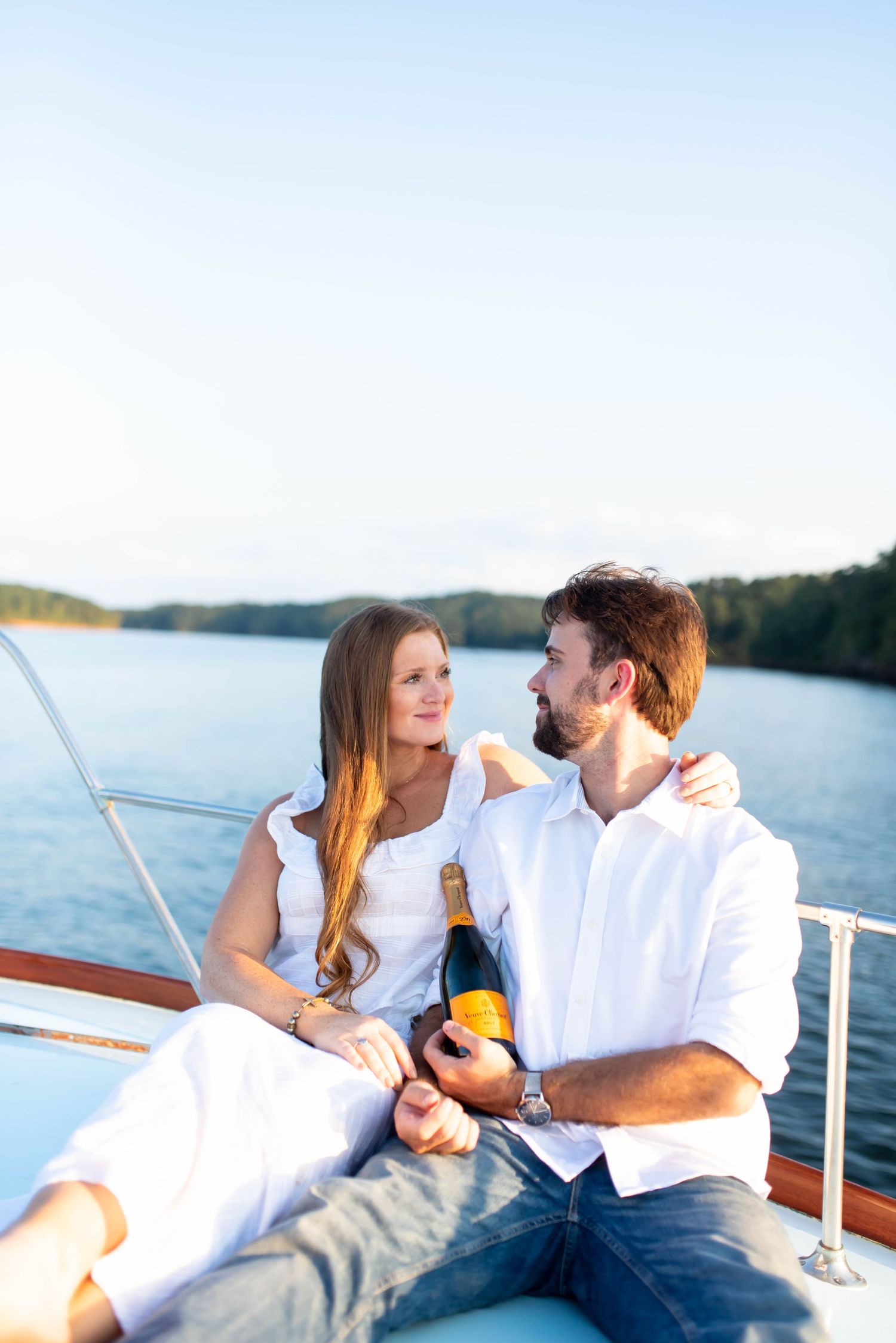 Couple relaxing on boat deck during sunset cruise over calm waters.